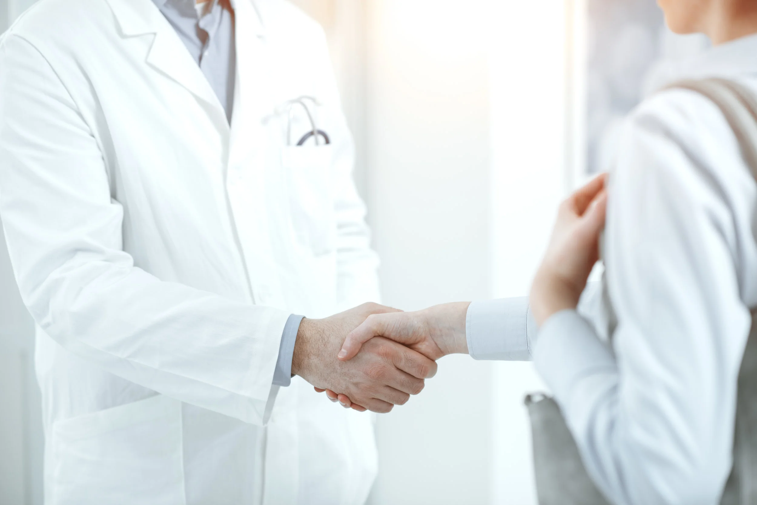 Doctor in white coat greeting his patient before standard appointment