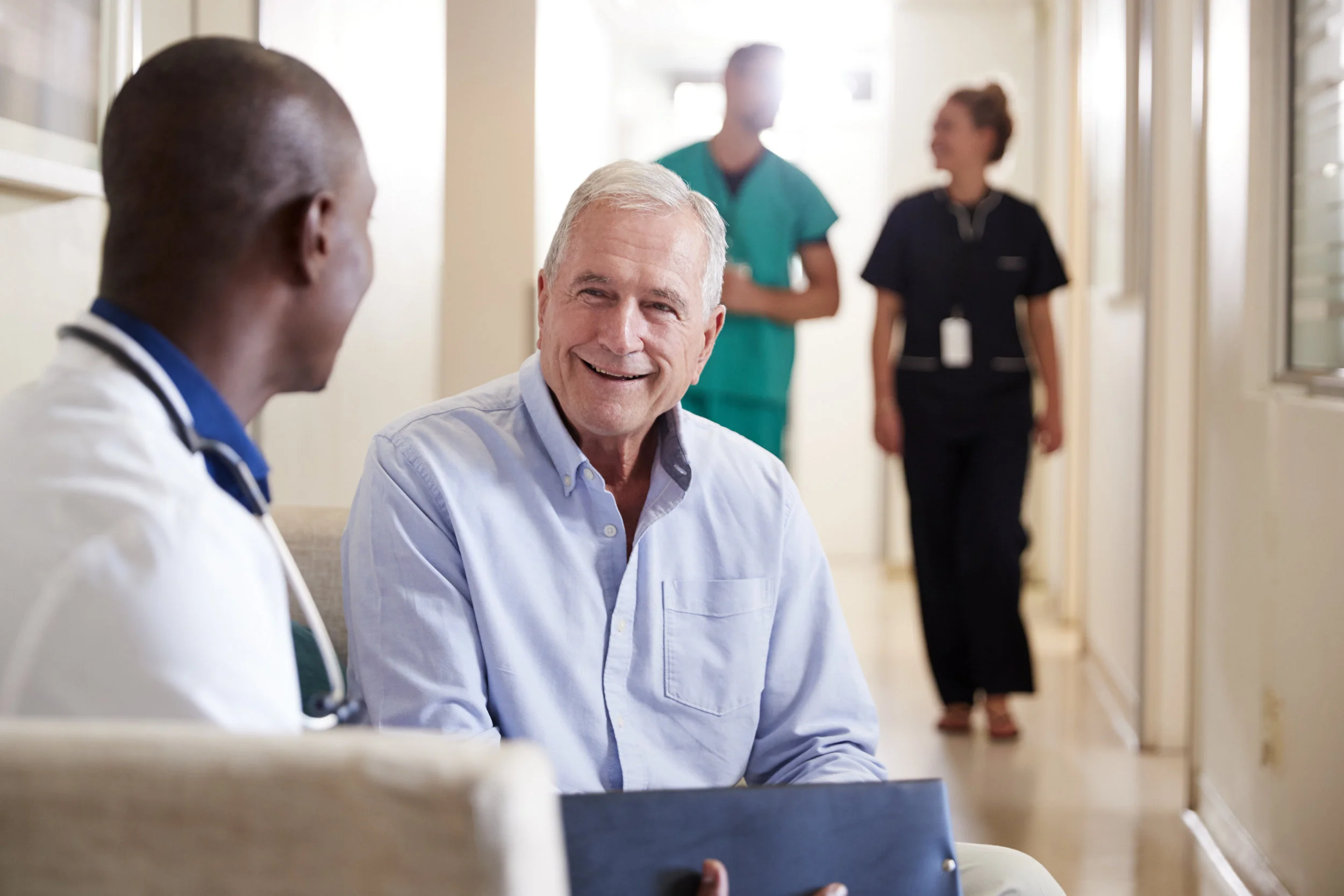 Smiling patient meeting with his doctor to talk about test results in hospital hallway