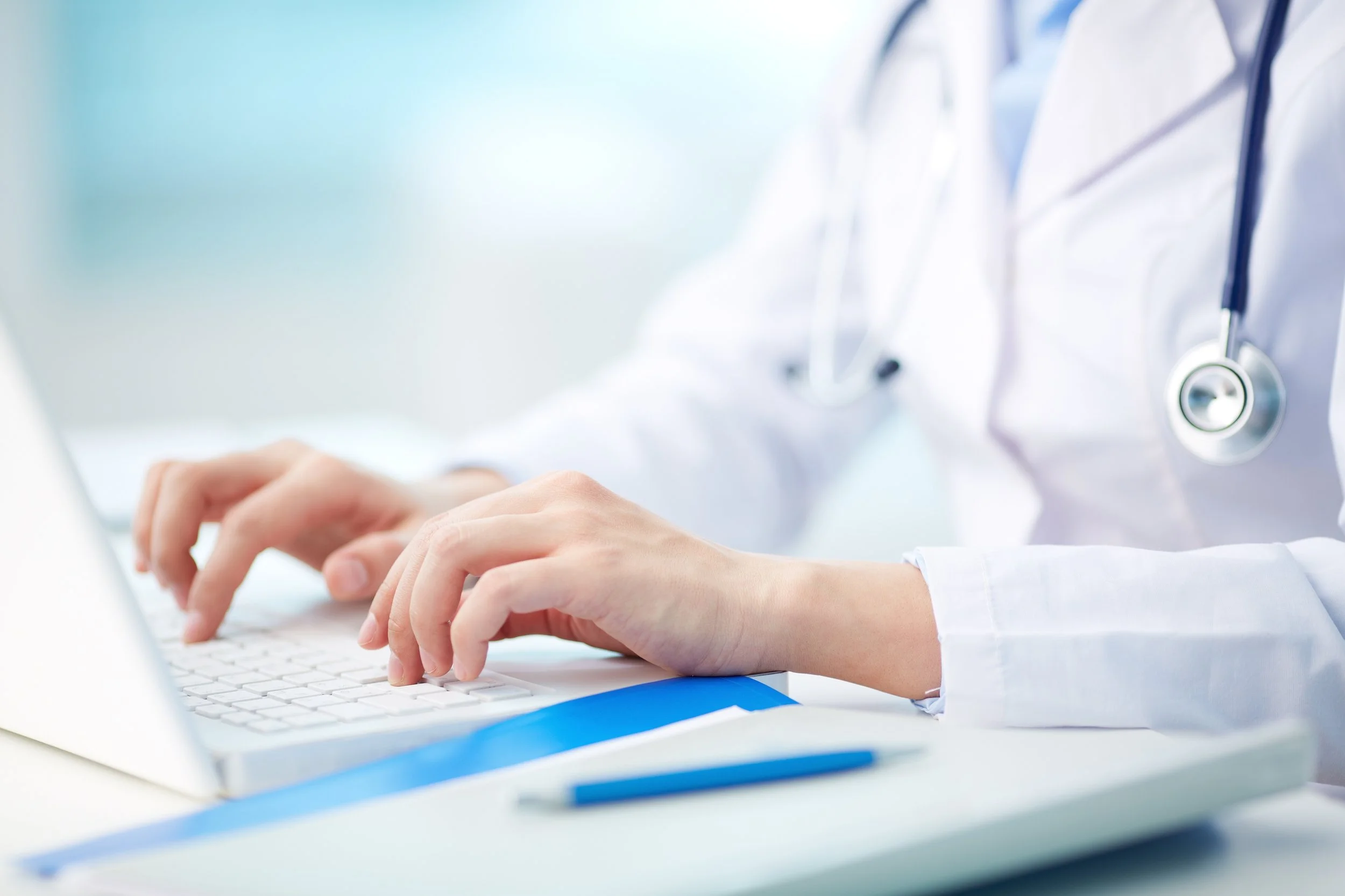 Medical doctor in white coat typing information into a computer