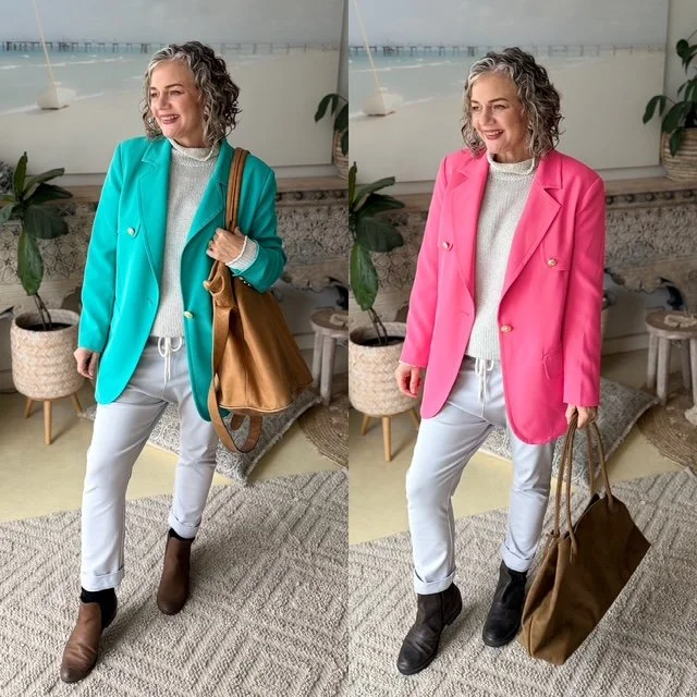 women grau hair curly standing gray pants dark boots holding handbag bright green blazer bright pink blazer'