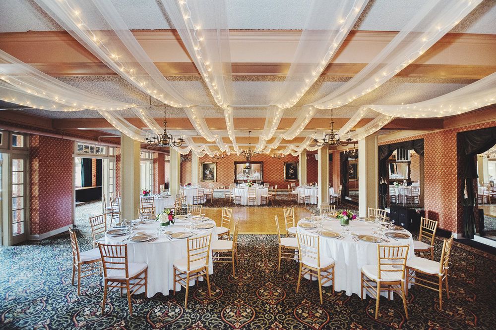 The Columbia Gorge Hotel ballroom set with tables of white linen and golden plates and chairs. 