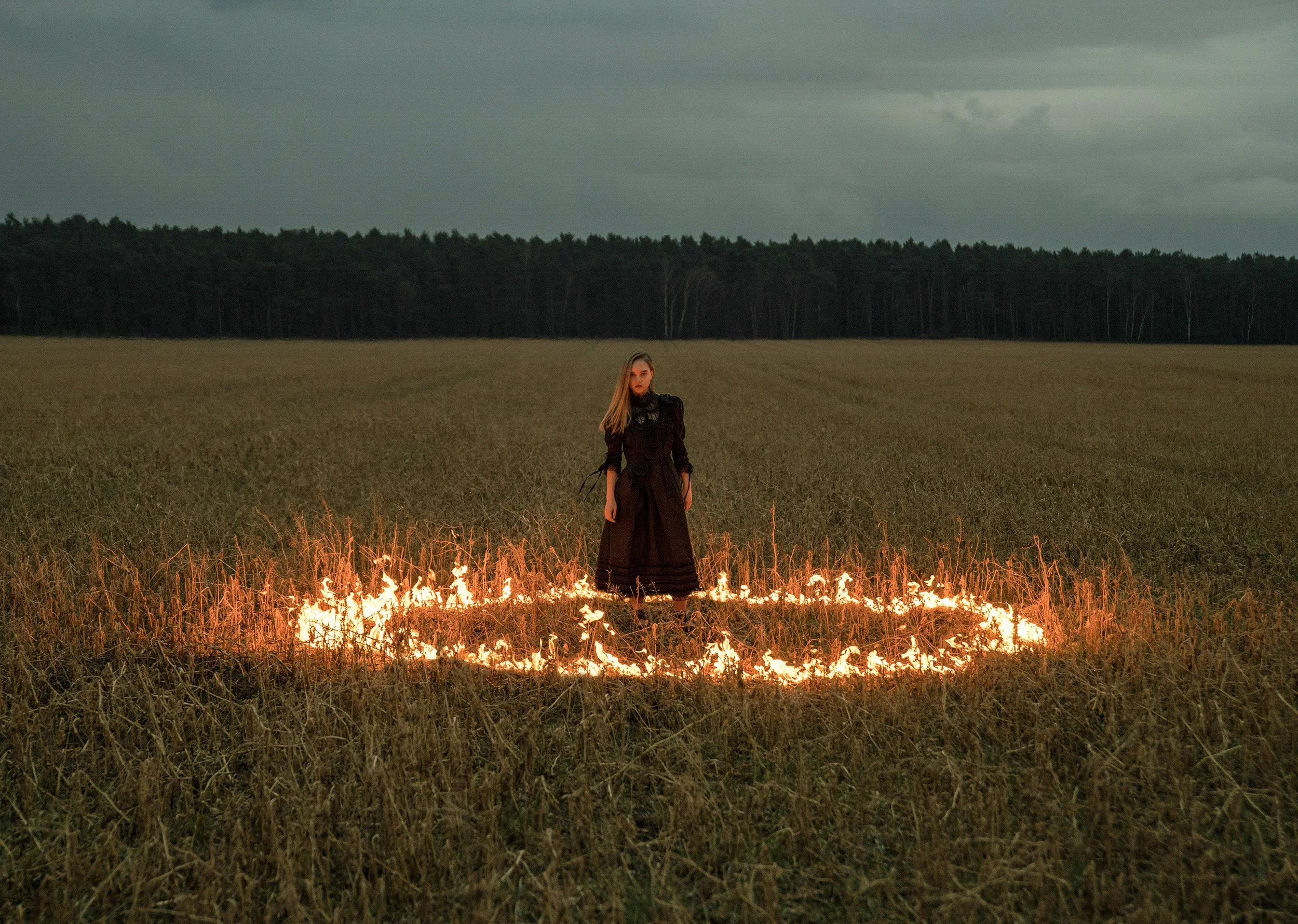 Katharina Nikelski in a field in Brandenburg. Black gothic lace dress by Marc Jacobs. Real fire / no AI