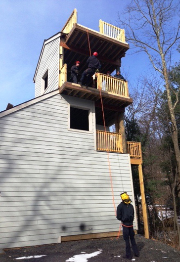 Junior Firefighter Peyton Galloway rappels from the 25' level of Wintergreen Fire & Rescue's new training tower while instructor Nick Brown offers pointers and firefighter/medic Eric nhold belays.