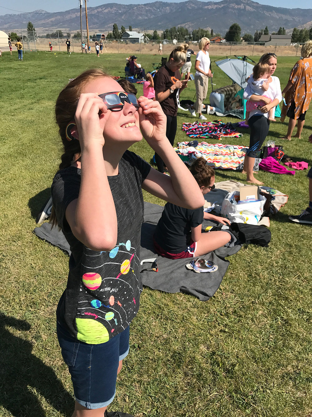 A girl watches the solar eclipse through eclipse glasses.