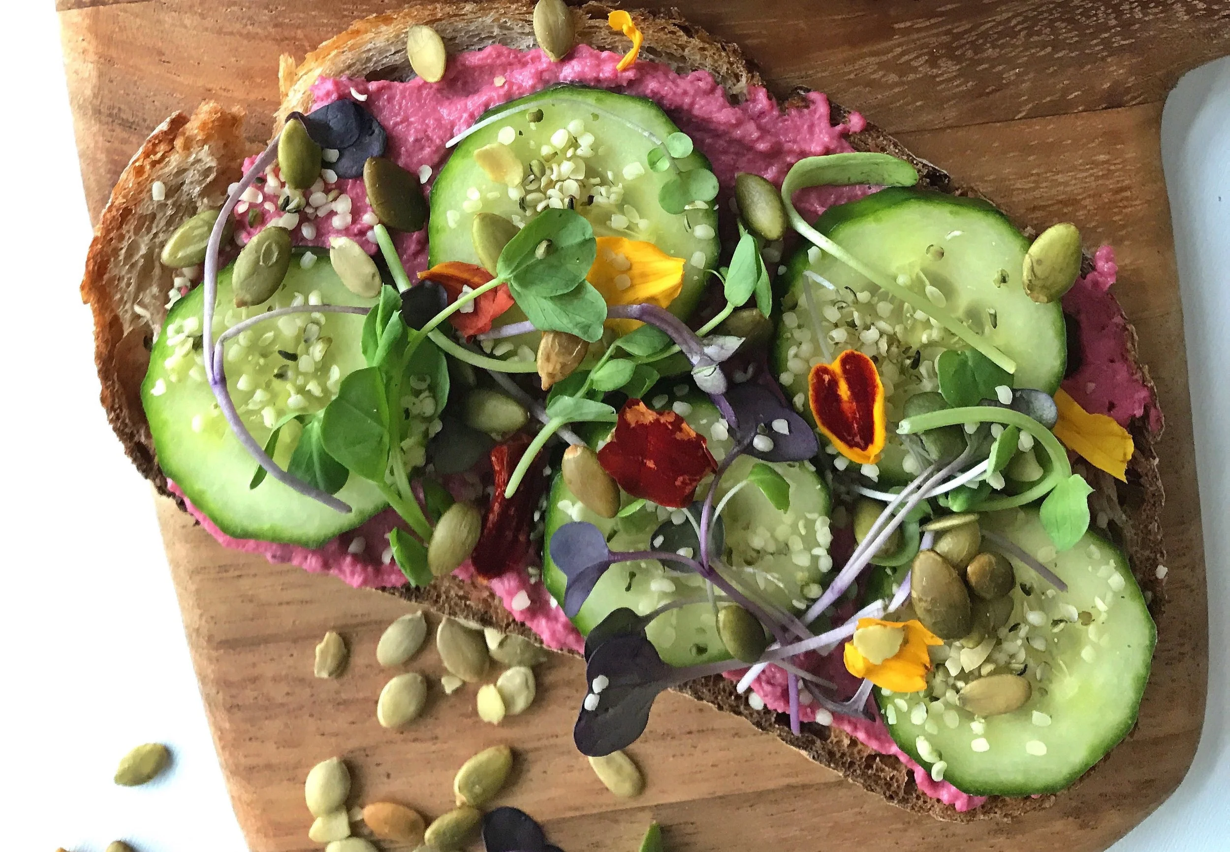 BEETROOT HUMMUS ON SOURDOUGH TOAST WITH CUCUMBER, MICROGREENS, PUMPKIN SEEDS & HEMP HEARTS.