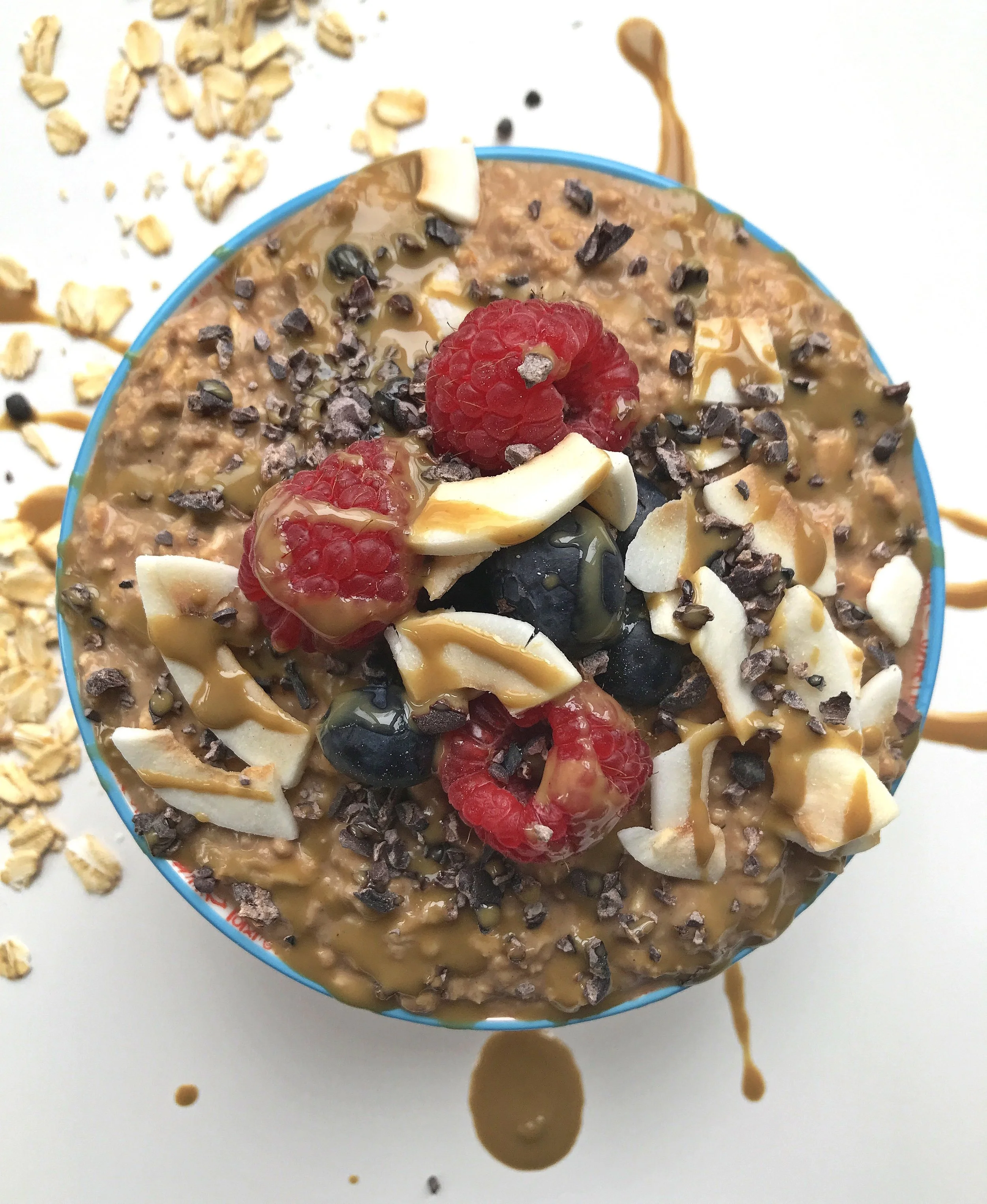 “REESE’S” PEANUT BUTTER PROBIOTIC PROATS MADE WITH KEFIR IN PLACE OF ALMOND MILK. TOPPED WITH BERRIES, CACAO NIBS, COCONUT CHIPS, AND SUNBUTTER MELTED WITH A TOUCH OF COCONUT OIL.