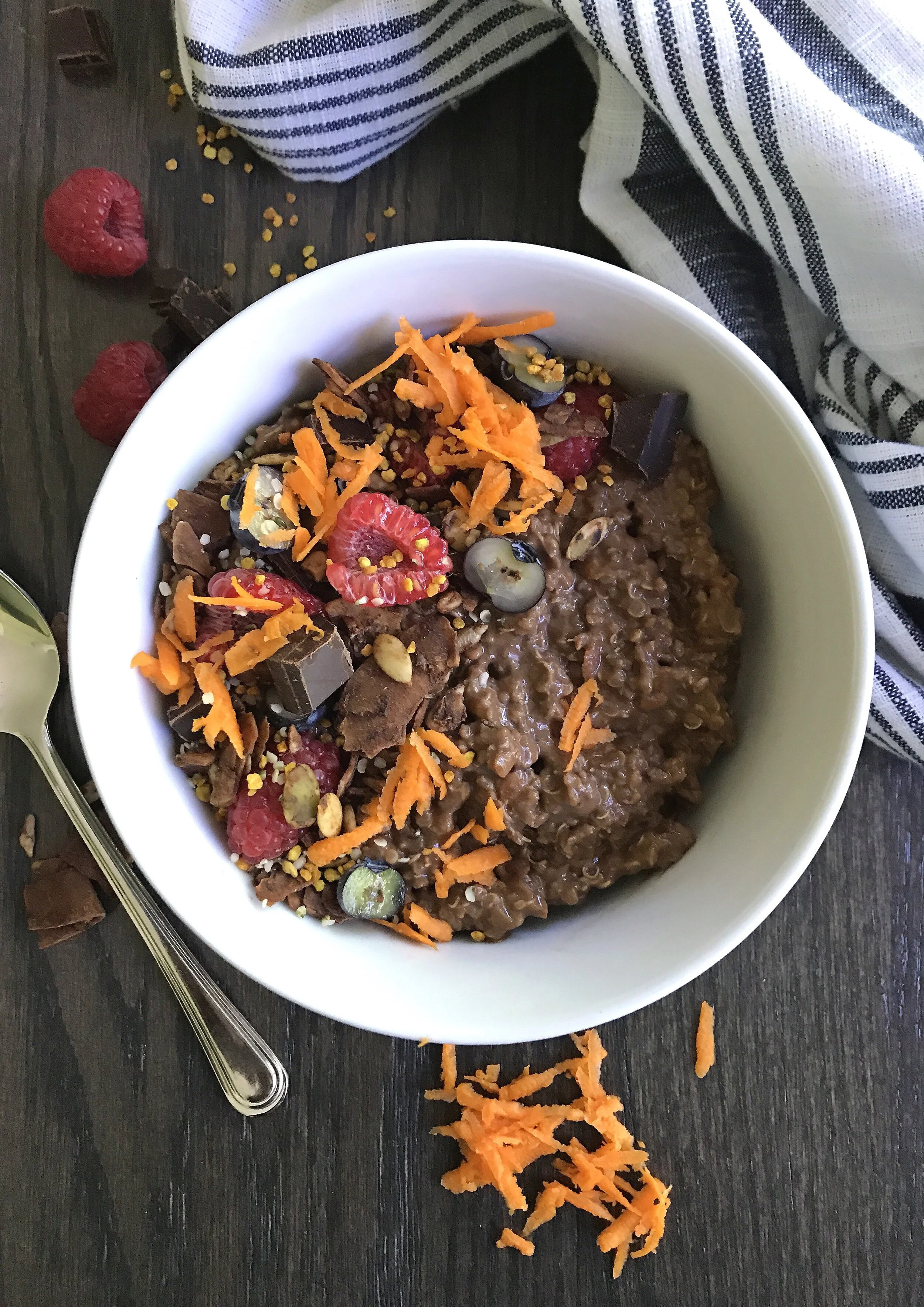 Chocolate Carrot Cake Quinoa topped here with organic blueberries & raspberries, GiddyYo 79% cacao chaga bar, chocolate grain-free granola, hemp hearts, bee pollen, and grated carrot.