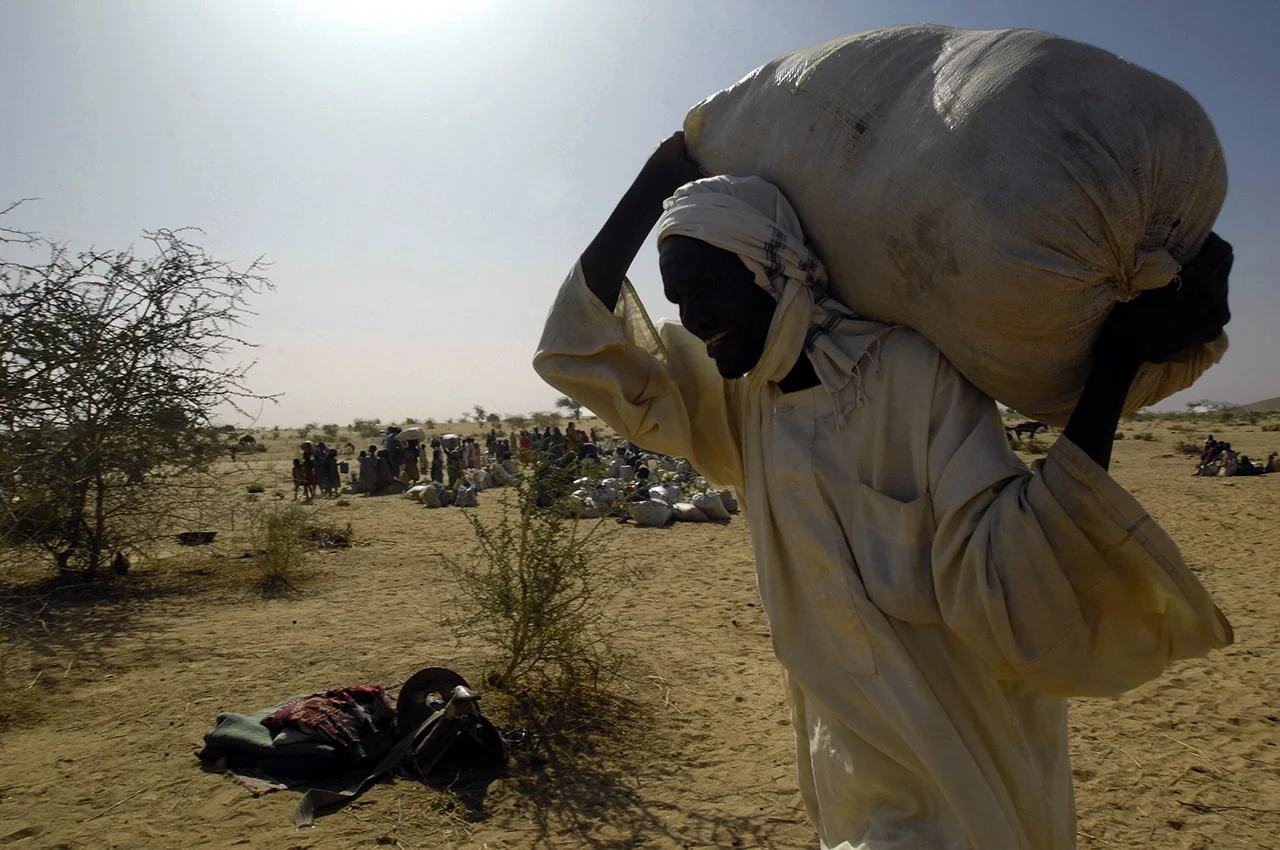 A refugee carrying food bag to a truck for the transfer to refugee camps near Guereda, 3 to 4 hours drive from Birak. 