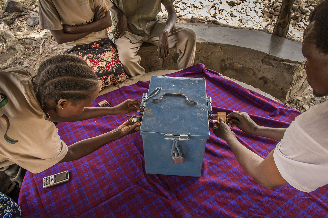Village of Nyichoka, about 30 kilometers west of the Serengeti, the members of the group "Sinduka Cocoba" gather around a table on which is placed a blue metal box closed by three padlocks After an immutable ritual, the box is unlocked. Four plastic