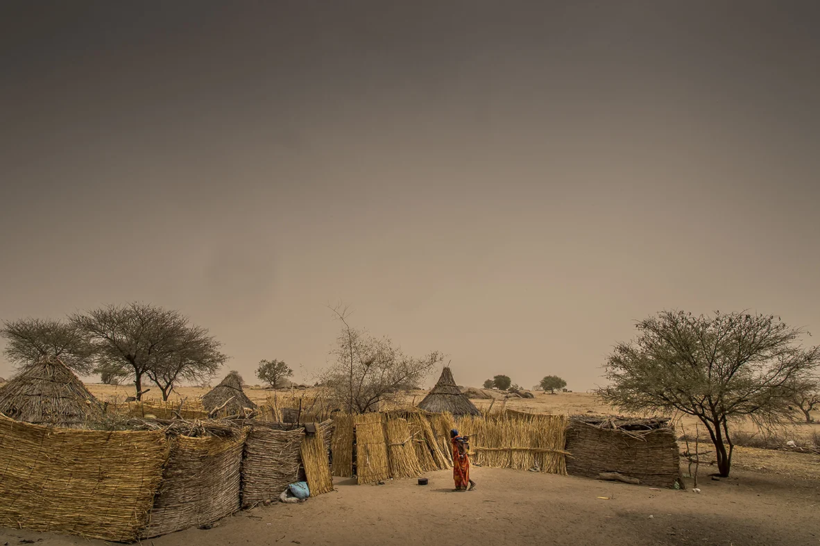 Assoungha district. The bush between Hadjer Hadid city and the village of Ourkoulong. An old woman comes to visit a friend, carrying on her back the child of her daughter who work in the family vegetable garden somewhere along a wadi, few kilometers away. 