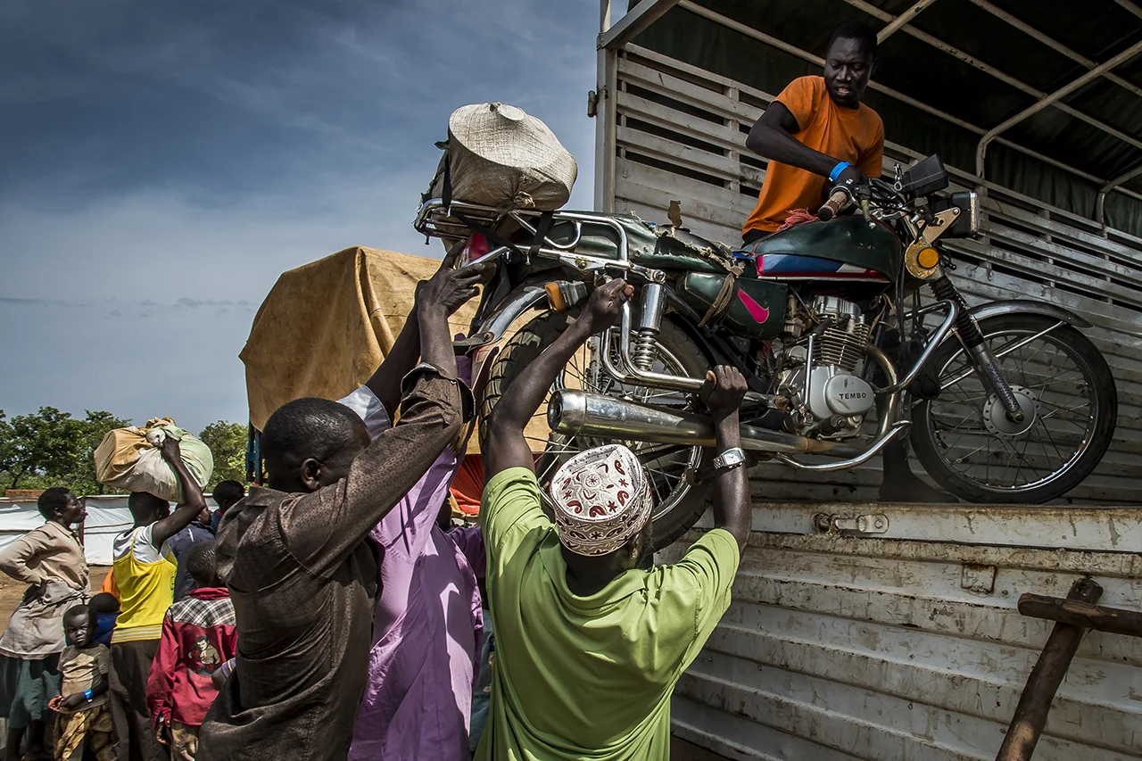 In the Goboro transit center, refugees help one of them to load a moped in a truck that will transport their luggage to the Imvepi reception center. Some manage to flee with minimal planning so that they do not arrive in Uganda totally destitute. From different points of entry along the border between South Sudan and Uganda, the refugees are gathered in transit centers where they are welcomed, fed and as quickly as possible taken by bus to the Imvepi reception two hours drive away.