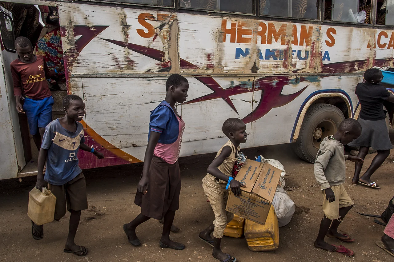 Imvepi, Center of reception. Some refuges get down of a bus which has taken them from one of the transit center close to the South Sudanese border. They carry the few belongings that they have manage to carry from South Sudan.