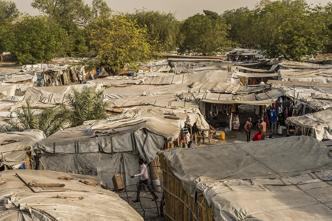 Old Fangak market where almost all the roofs of the stalls are waterproofed thanks to a tarpaulin distributed to the displaced people by UNHCR to build a tent. old Fangak is a city located along the Phow River (Bahr-el-Zeraf or Giraffe River), a tributary of the Nile, in Jonglei State about 100 kilometers south of the city of Malakal. It is called Old Fangak because the city was temporarily abandoned in 1977, and the county offices moved to Phom-el-Zeraf (New Fangak). Located in northeastern South Sudan, Old Fangak is home to mainly Nuer people in one of the largest swamps in the world, the Sudd. No roads, only accessible by boat or small plane. Before the Civil War, Old Fangak had about 5,000 people, and another 10,000 lived nearby. But the war has changed everything. The small rural village has become a refuge for people fleeing the fighting along the Nile. Since 2014, some 45,000 displaced people have taken refuge in Old Fangak.