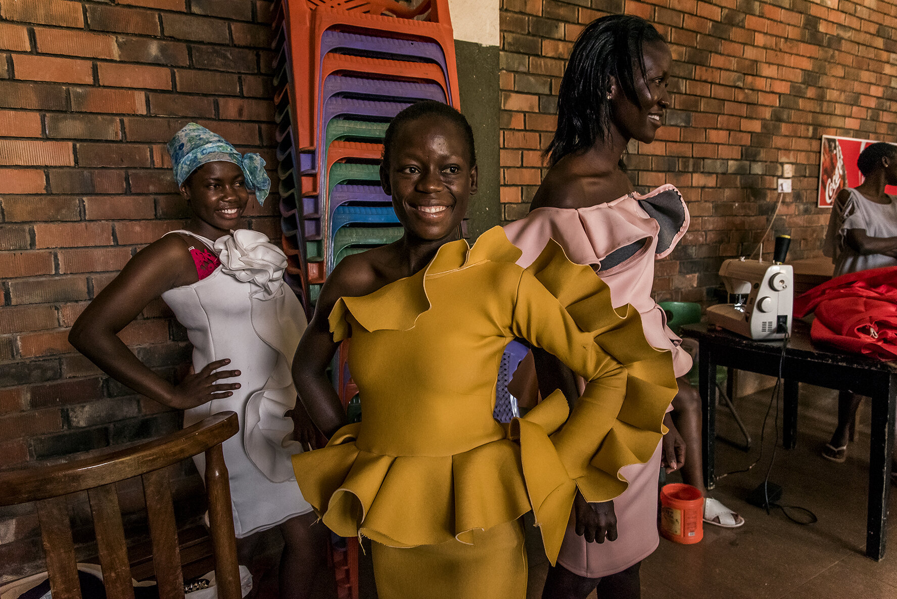 The female candidates try on their outfits during the final fitting and adjustment session, the day before the final, in a common room adjoining the hotel where they spend the night. Ugandan girls and women face a higher risk than boys and men of co