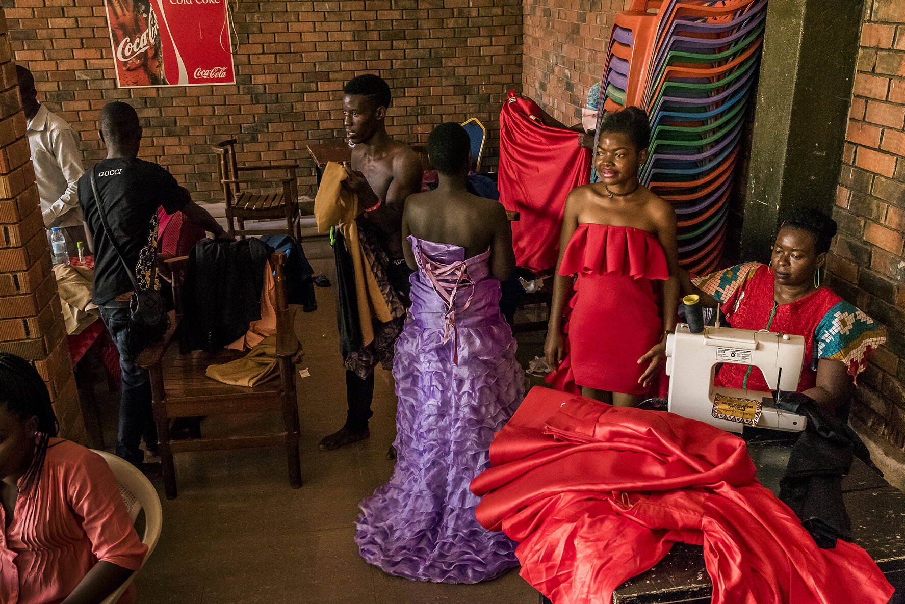 In a common room adjoining the hotel where the sixteen Y+ candidates spend their last night before the competition, the candidates try their outfits allowing a seamstress to make the last modifications.