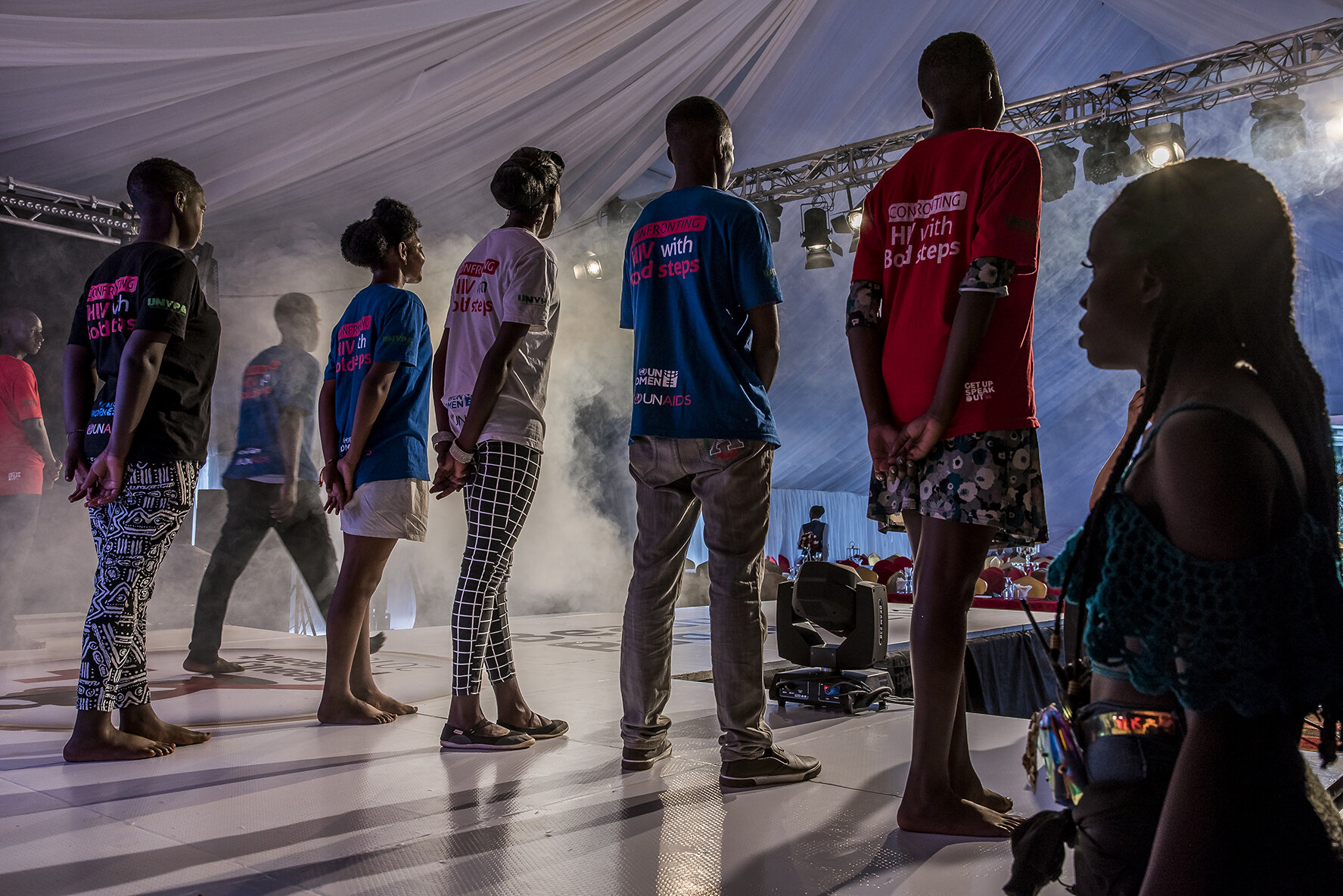 Two hours before the beginning of the final, under the eyes of the boys' coach, the sixteen stressed candidates carry out a final set-up on the stage where the beauty contest will take place, in a luxury hotel in the center of Kampala. Seven girls a