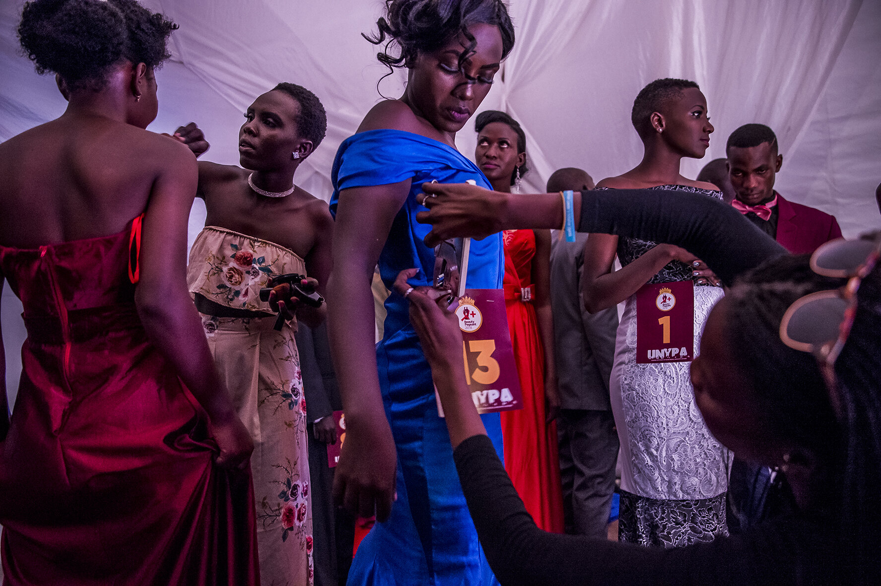 Behind the scenes, a make-up artist is touching up the makeup of a candidate, while a dresser staples the time number on the waist of Vivian Nabanoba’s dress, the future winner of the competition. Besides walking away with a full year scholarship fi