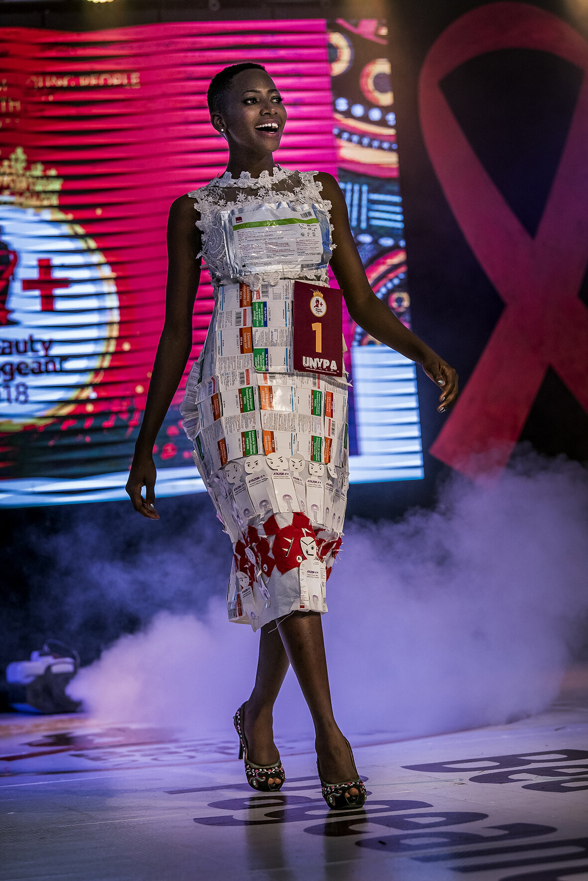 During the final events, Sherina compete in an outfit she made during the week of preparation and retreat. The only requirement for this event is that the costume must carry a message. Sherina appears in a white dress made of HIV retroviral packagin