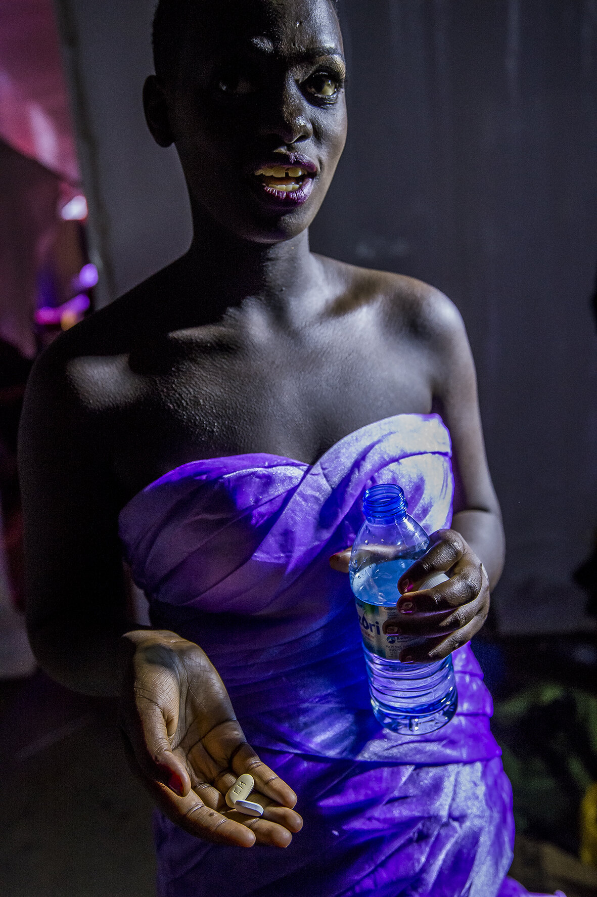 From two plastic bottles carried in her bag, Hajarah draws two long tablets. At 10 p.m. every day, she has to take her antiretrovirals. That day, she does it backstage during the beauty pageant, before the results are announced.
