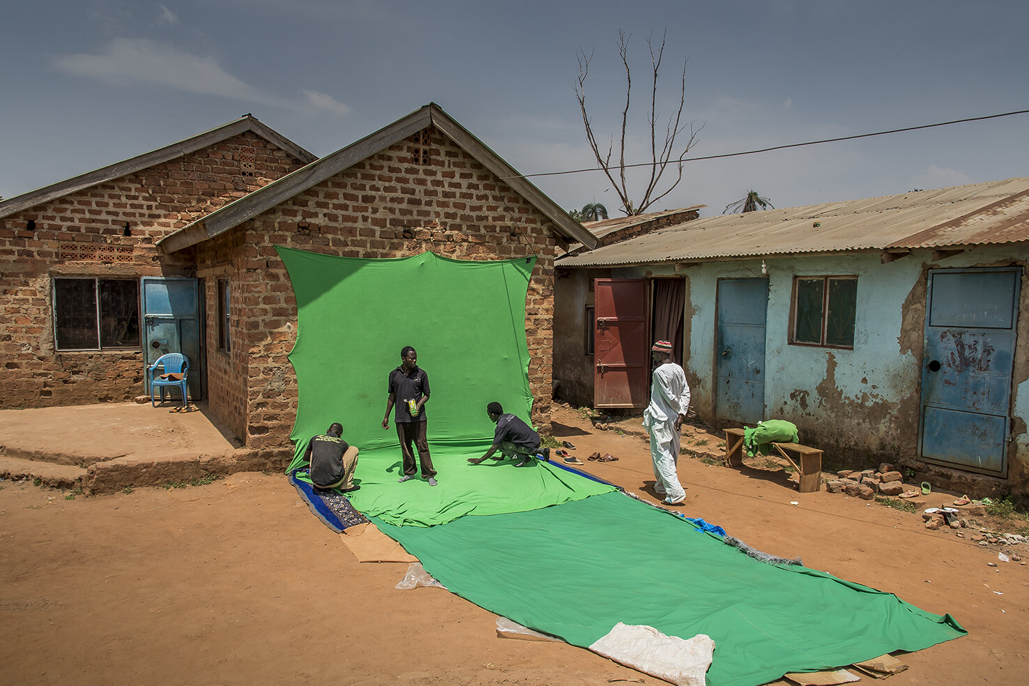  Comedians-technicians set on a wall of Isaac Nabwana house (ICG) a green chroma key background to make incrustations in post-production, for the special effects. The house of ICG is divided in 2 parts. One where he lives, another where his editing s