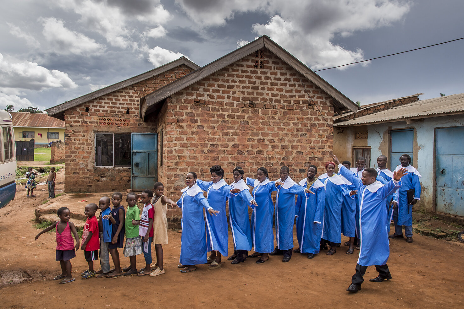  In the family compound of Isaac Nabwana, main set of Wakaliwood (Isaac’s house is the one in red bricks), a video clip is shot. The singer, Ronald Buryahika (arms wide opened) is a Wakaliwood actor and religious hits singer. He wants to post his cli