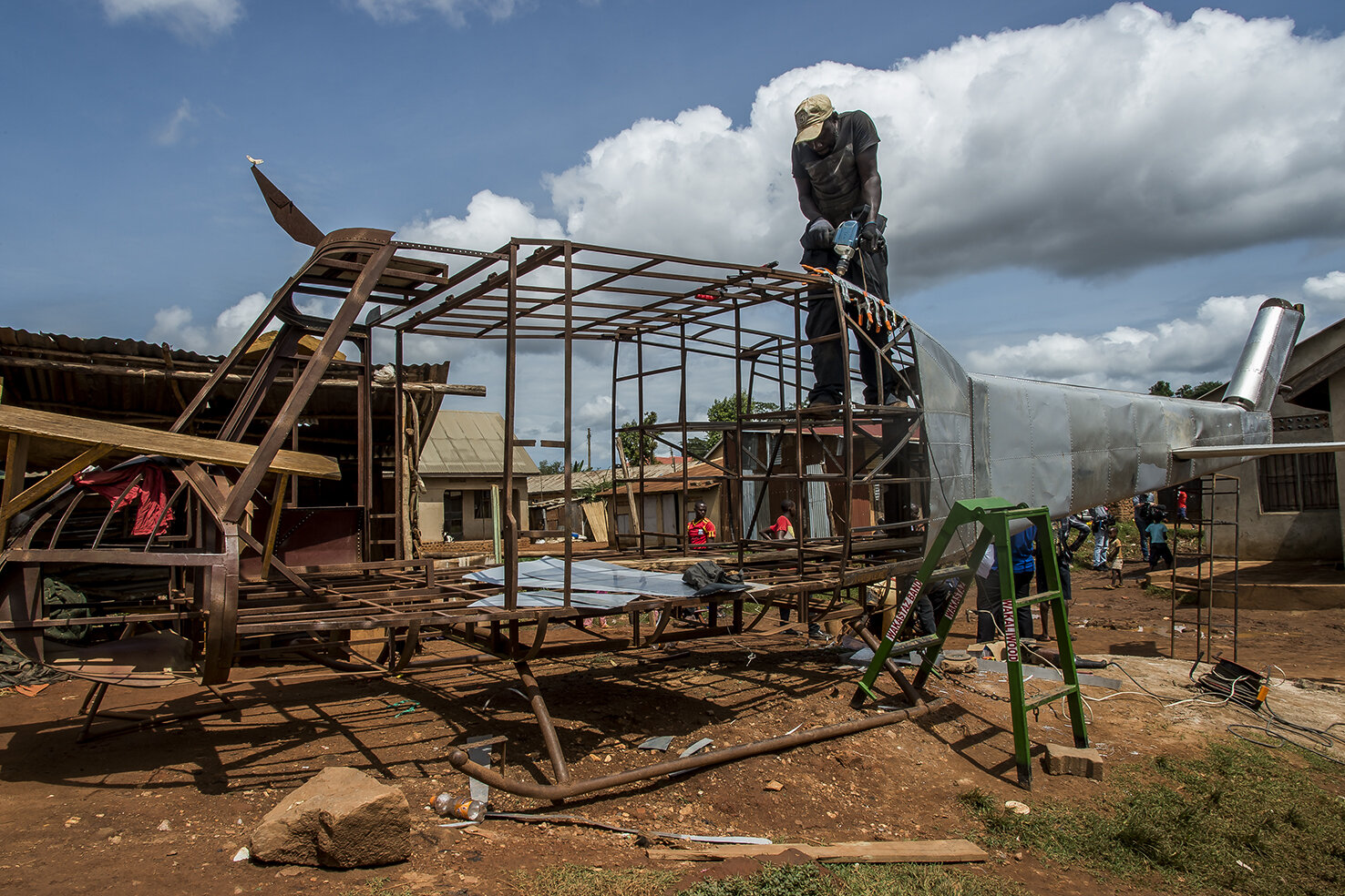  One day, Daouda Bisaso, the prop-man heard Isaac Nabwana says that a chopper could be a nice prop to shoot action movie. Never mind. In the courtyard of Wakaliwood, Daouda builds an helicopter, using salvaged pieces of iron and buying sheets to make