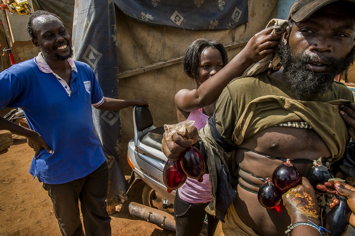  While Isaac Nabwana looks on and jokes, Ritha, the heroine of the movie series « Who killed Captain Alex » dust the back head of Apollo. In the same time, Isaac’s wife prepare the special effect of blood geyser spurting out of a shot vilain body. Co