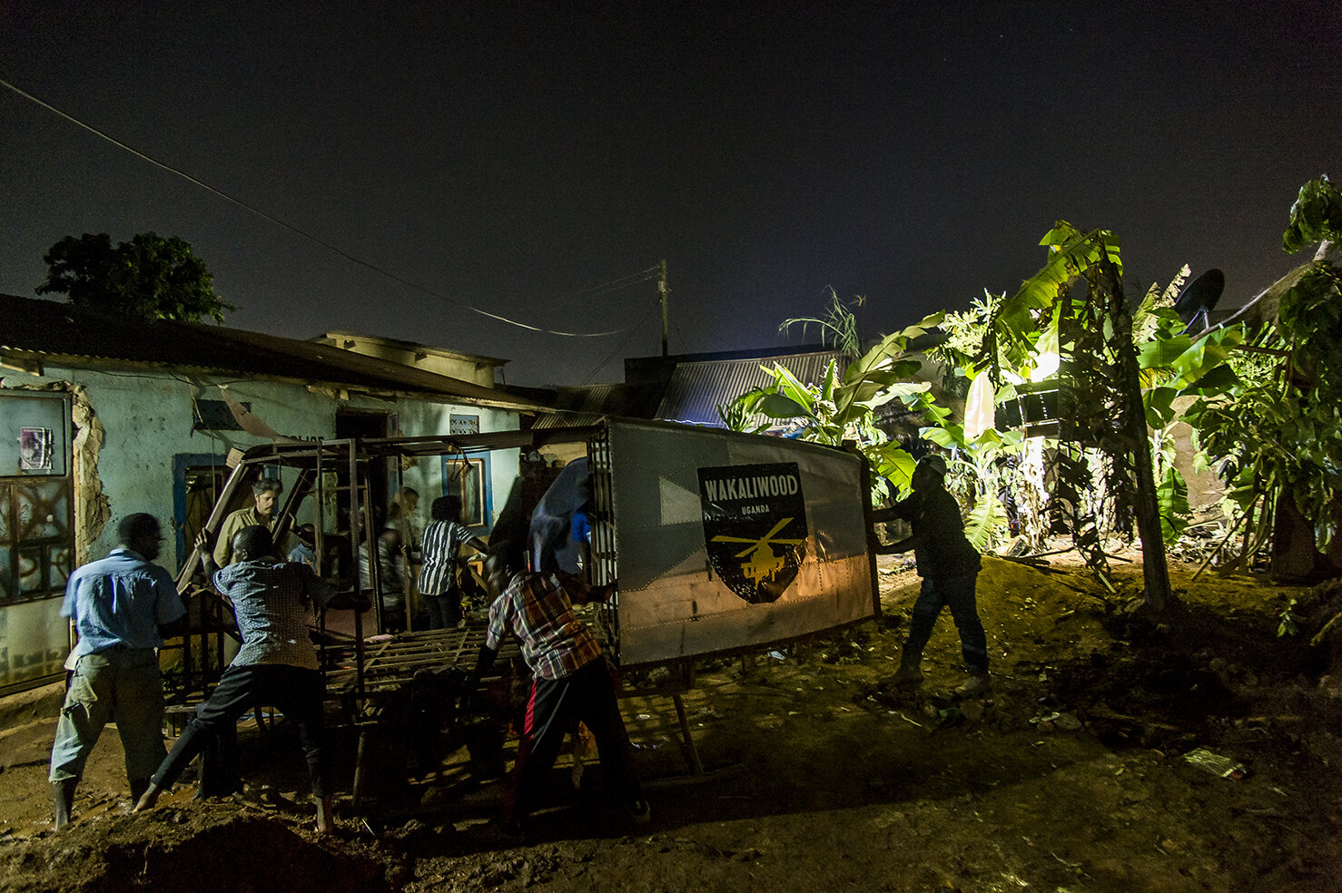  The actors move away the chopper to get enough space for the shooting of the night sequences of «&nbsp;Eaten Alive&nbsp;», in the courtyard of Wakaliwood. The set is a village where lives some cannibals / zombies. It was build in the afternoon by th