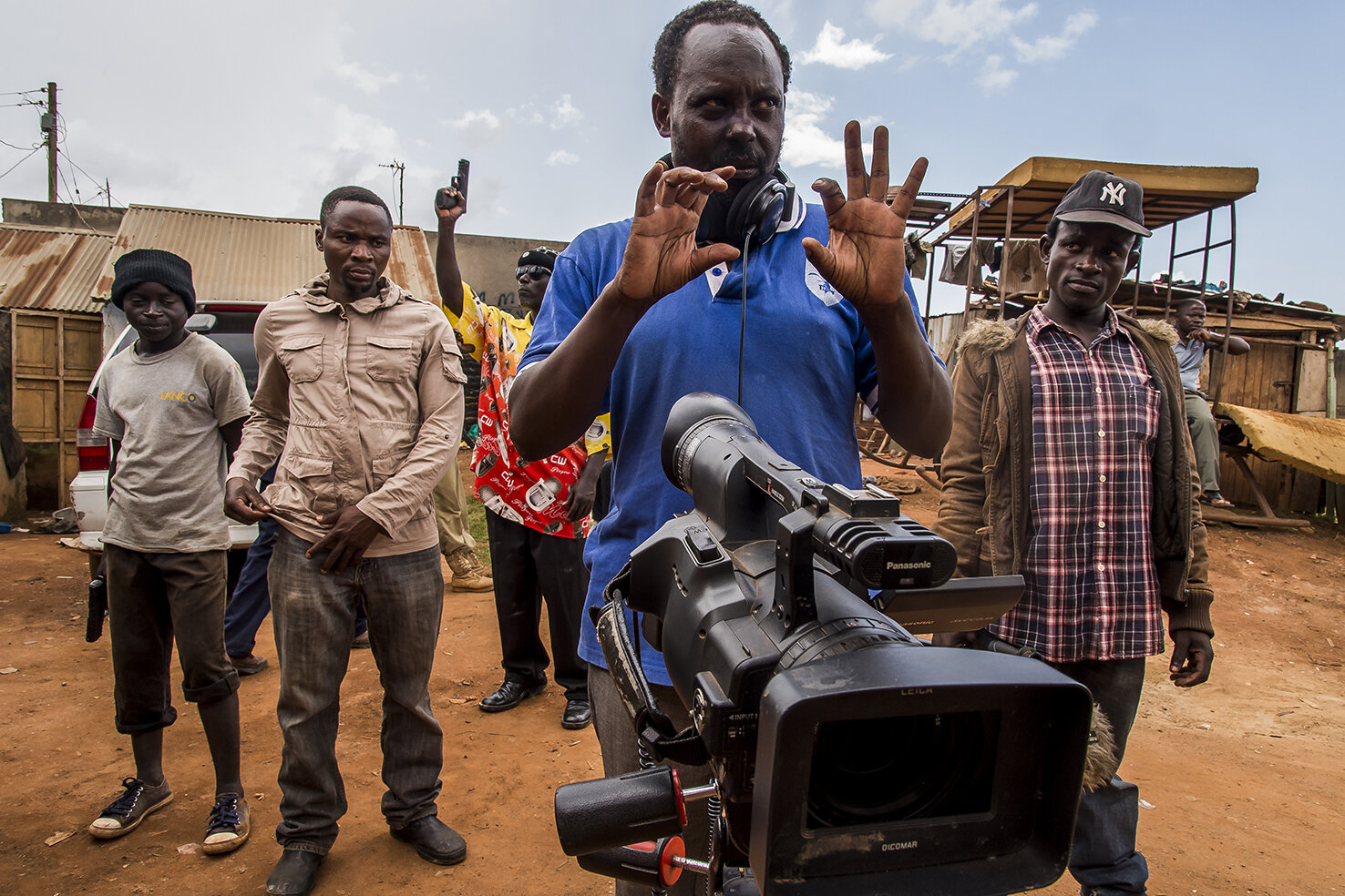  In Ramon Studio, a family compound in Wakaliga slum, Isaac Nabwana, the director of Wakaliwood, looks for the frame of the next shot while his actors look on. 
