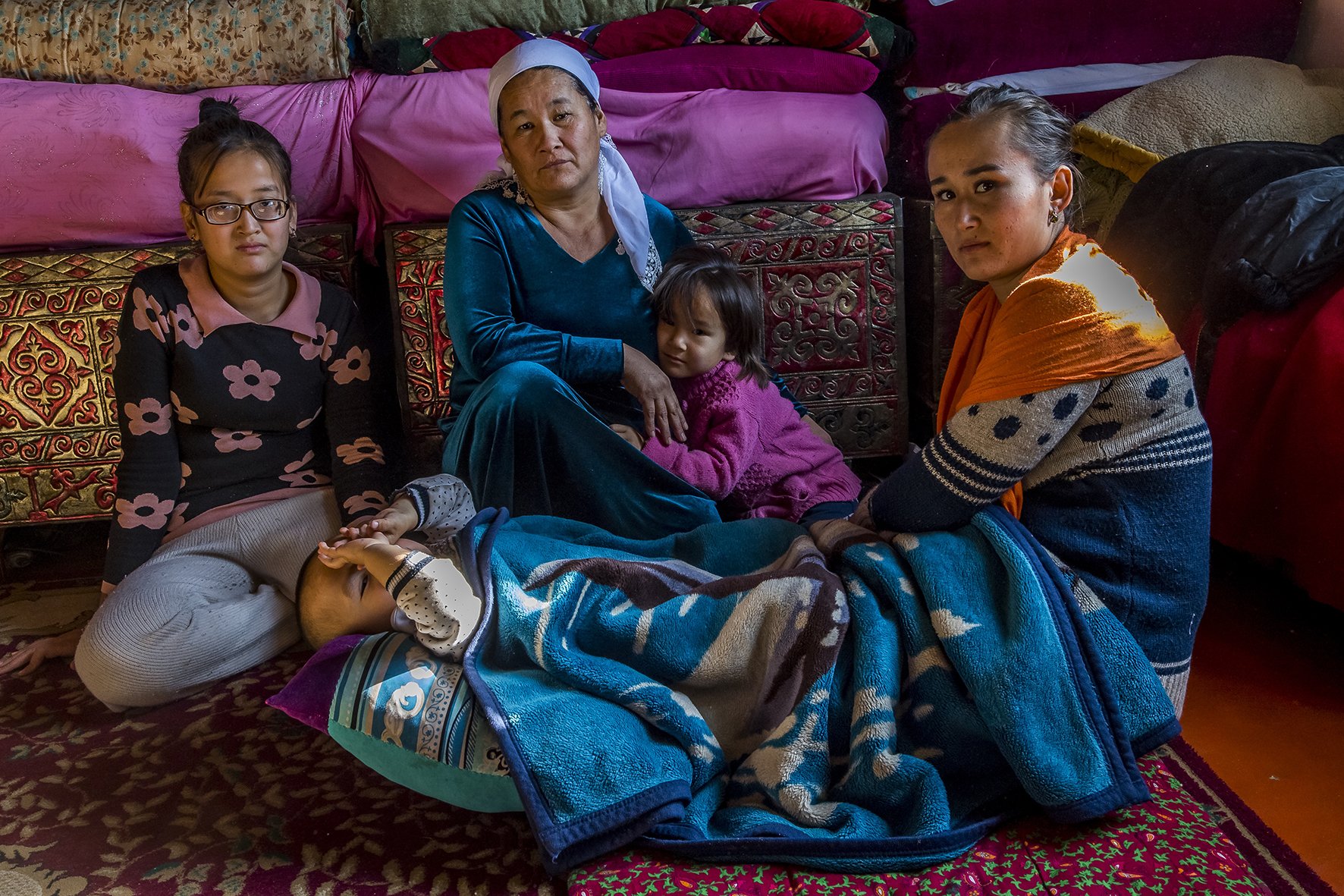 La famille « Qandas » de Zukhra Mukanova (foulard bleu), dans le salon familial, village de Chubarsu, proche de Chymkent. Le terme Qandas signifie littéralement de même sang et a remplacé le mot Oralman (les retournés) utilisé aupar