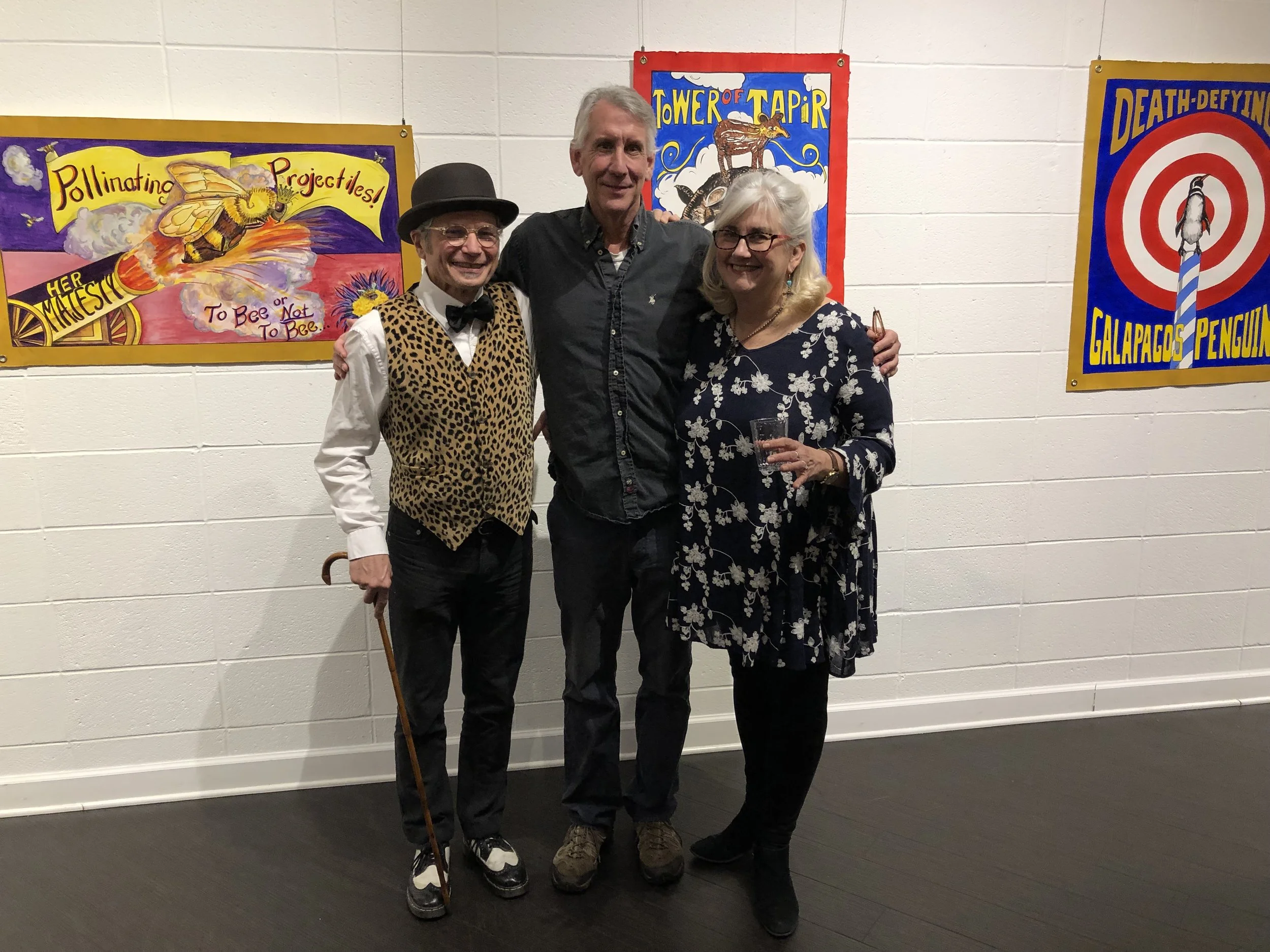 Joe (left) and Bess surround ECI Executive Director Jim Poyser at an exhibit at the Harrison Center for the Arts in January, 2019.