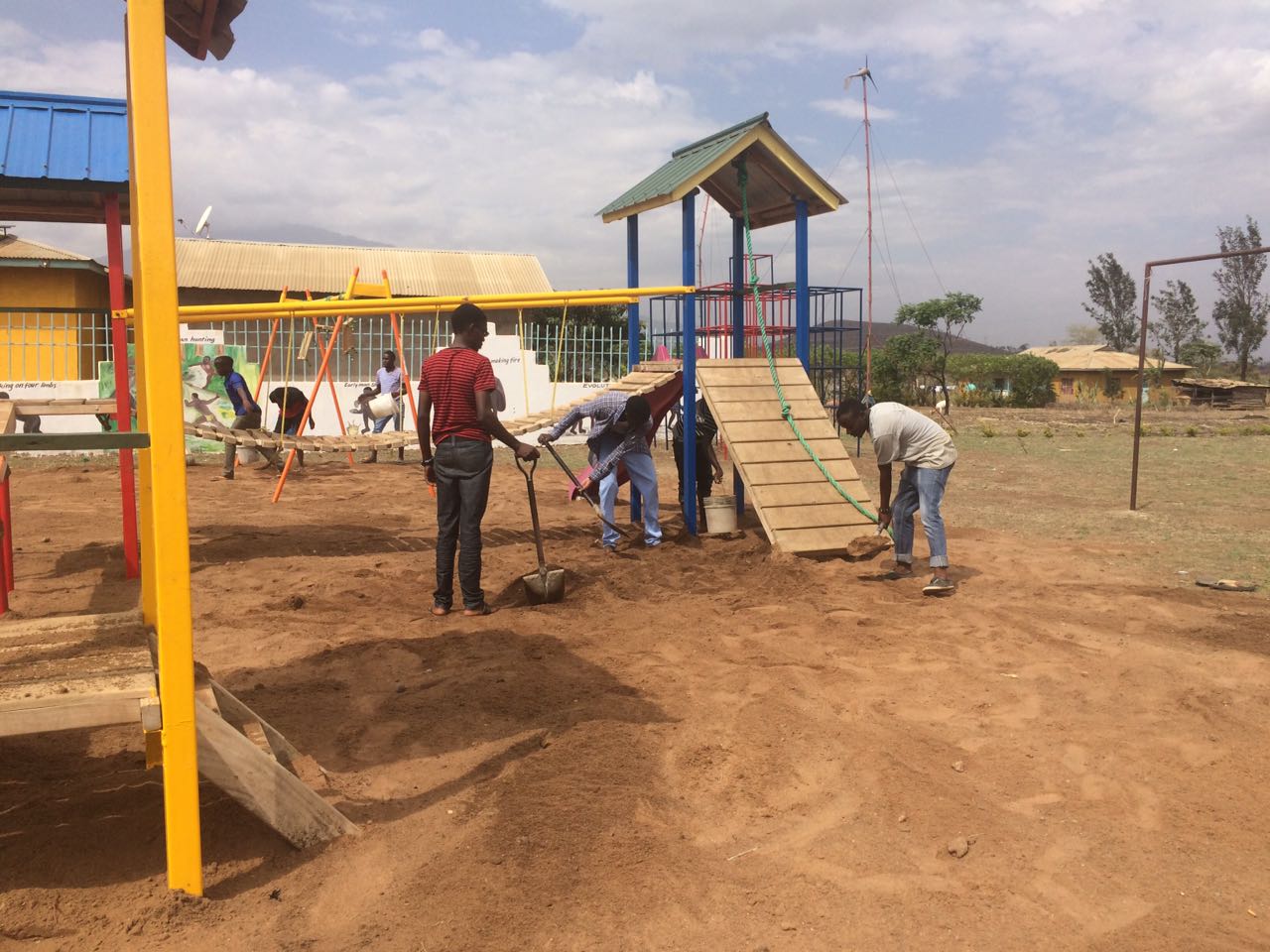 Laying sand on the new playground, which includes top-quality climbing systems made by IBES in Usa River and donated by the Unite For Africa Student Club in Darien, CT. 