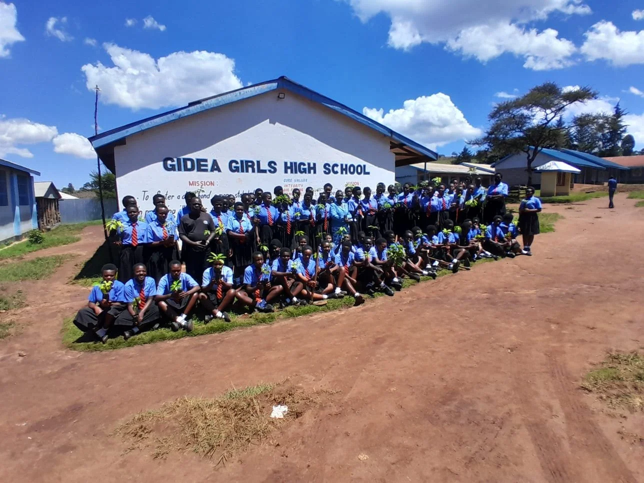 2025.11.13_ Gidea girls club members with trees ready to plant in school compound.jpeg