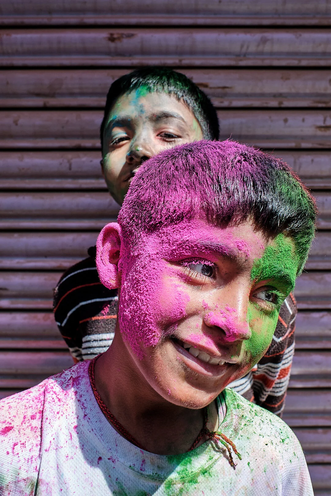 Two boys covered in colorful Holi powder laughing during Holi festival in Nepal — documentary portrait by Oliver Maximilian, KULTURHYBRID®