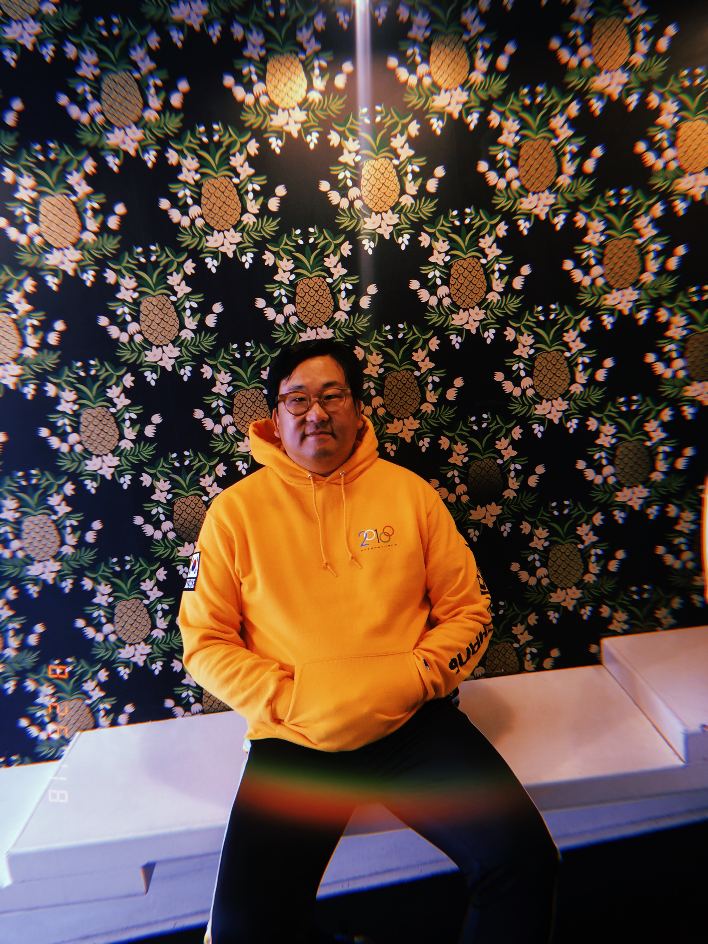 Nick Cho in front of the store's famed pineapple wallpaper by Rifle Paper Co.