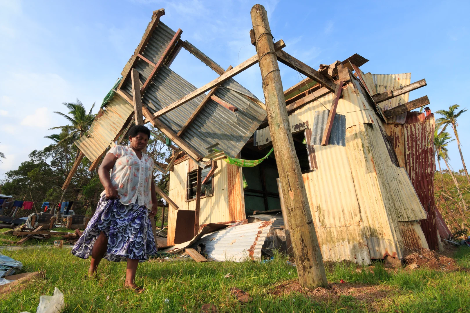 A woman from the village of Namena in Tailevu, Fiji, walks in front of her damaged house after Cyclone Winston swept through the area on February 20, 2016.