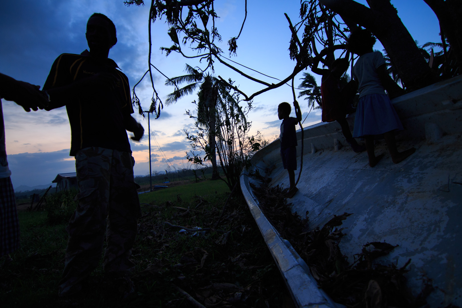  A man from Drau-ni-ivi Village in Rakiraki gestures as children play in the hull of an overturned boat behind him after Cyclone Winston swept through the area and made landfall in Fiji on February 20, 2016. 