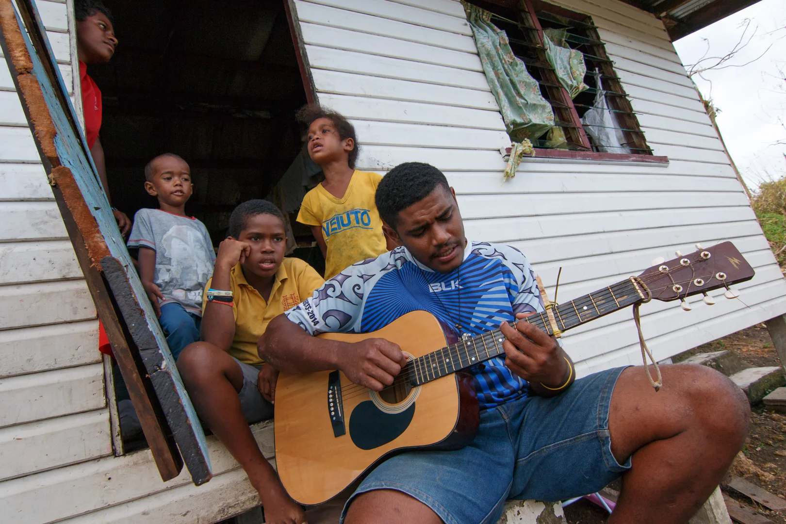 Children play guitar and sing songs to pass time while cleanup is underway in Naiseralagi village in Rakiraki, Fiji, after Cyclone Winston swept through the area on February 20, 2016.