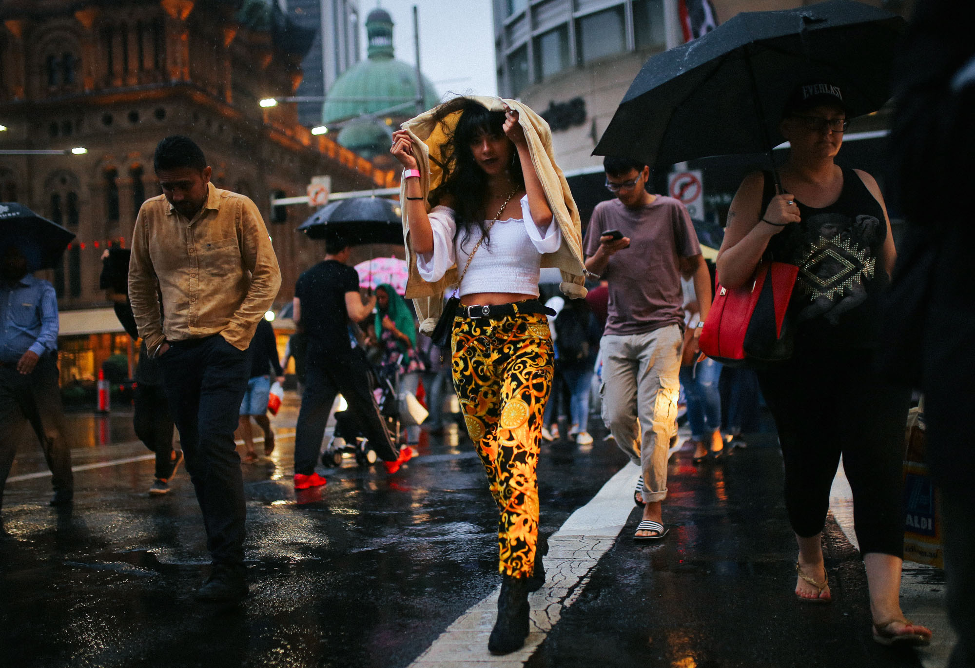  A woman shelters herself from the rain as she crosses the street with other pedestrians during a rain shower in central Sydney, Australia. 