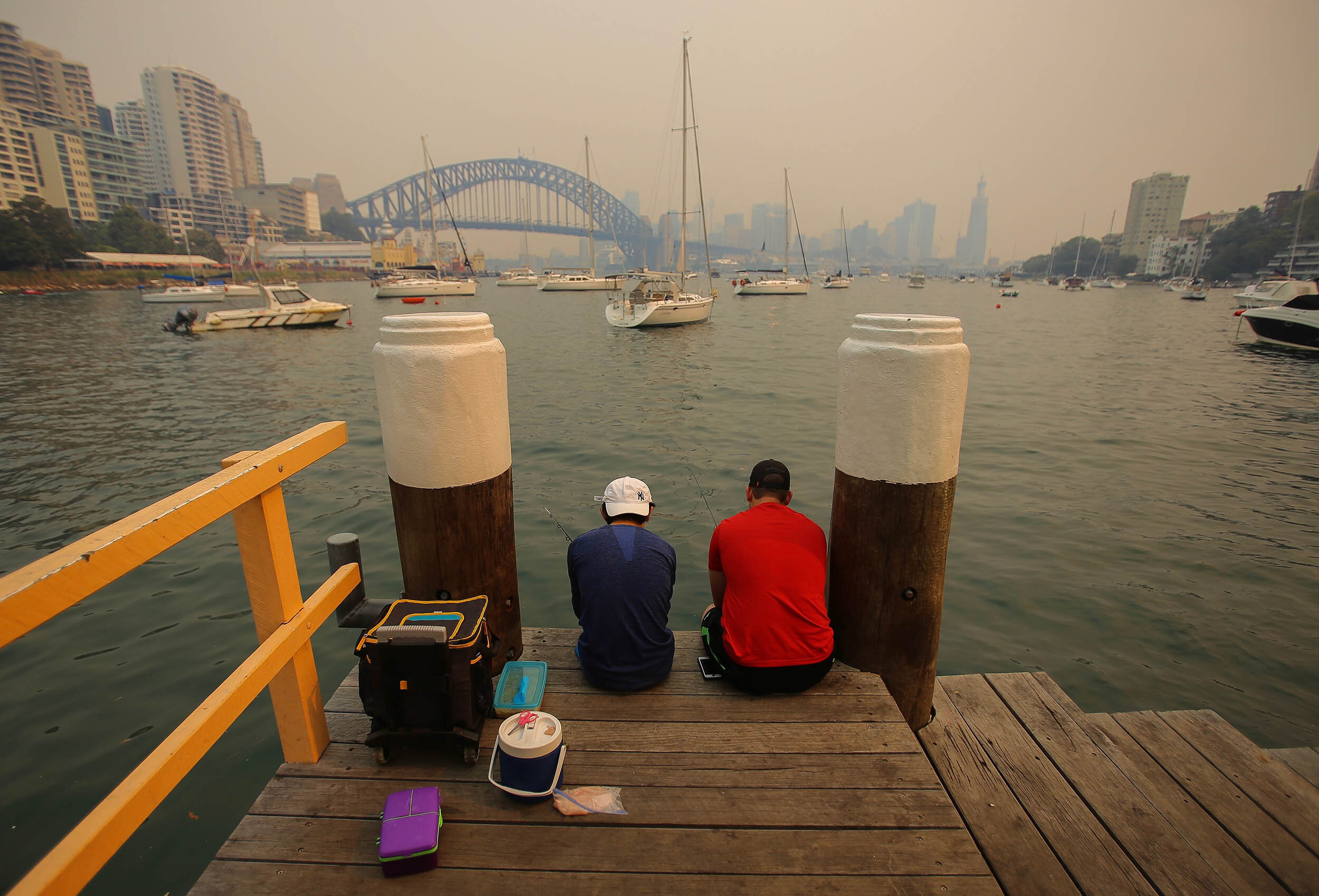  Two boys fishing from a jetty in Lavender Bay as smoke haze from bushfires in New South Wales blankets the CBD in Sydney, Thursday, December 5, 2019. (AAP Image/Steven Saphore) NO ARCHIVING 