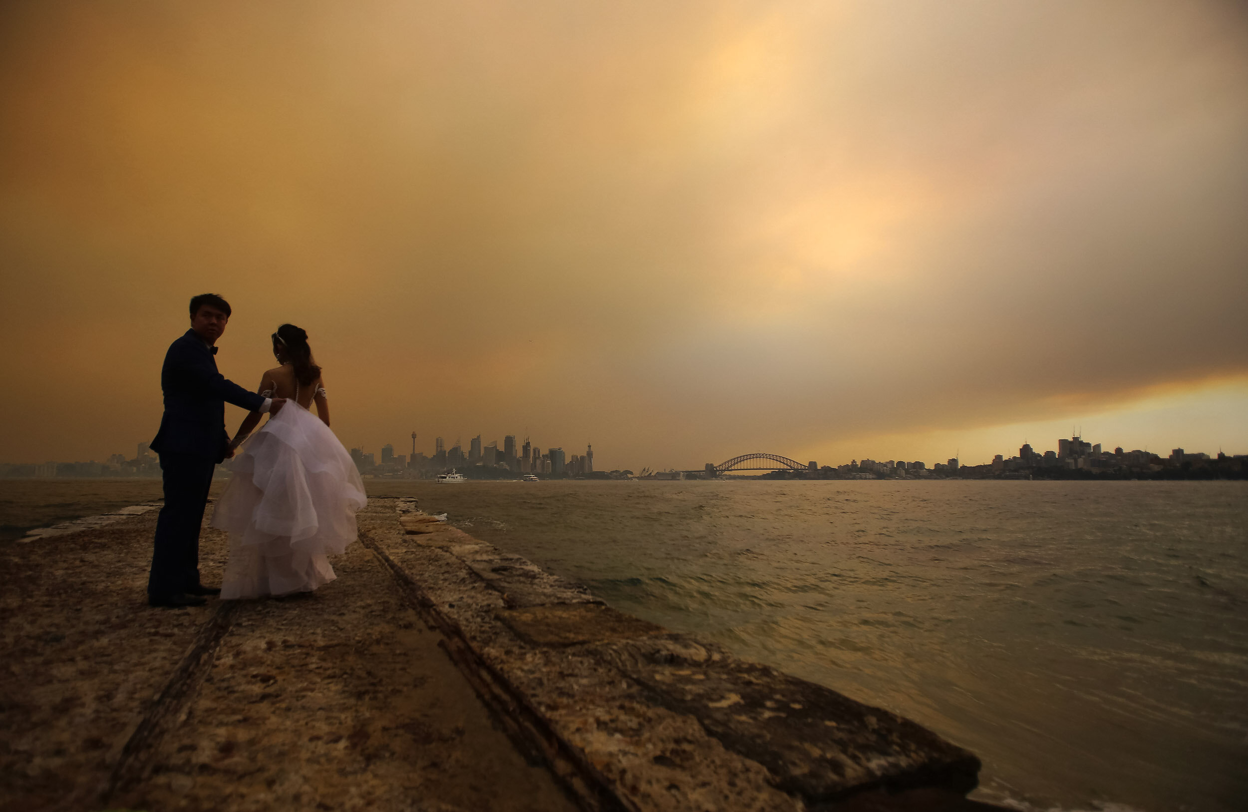  A couple have wedding photos taken as smoke haze from bushfires in New South Wales blankets the CBD in Sydney, Thursday, December 5, 2019. (AAP Image/Steven Saphore) NO ARCHIVING 