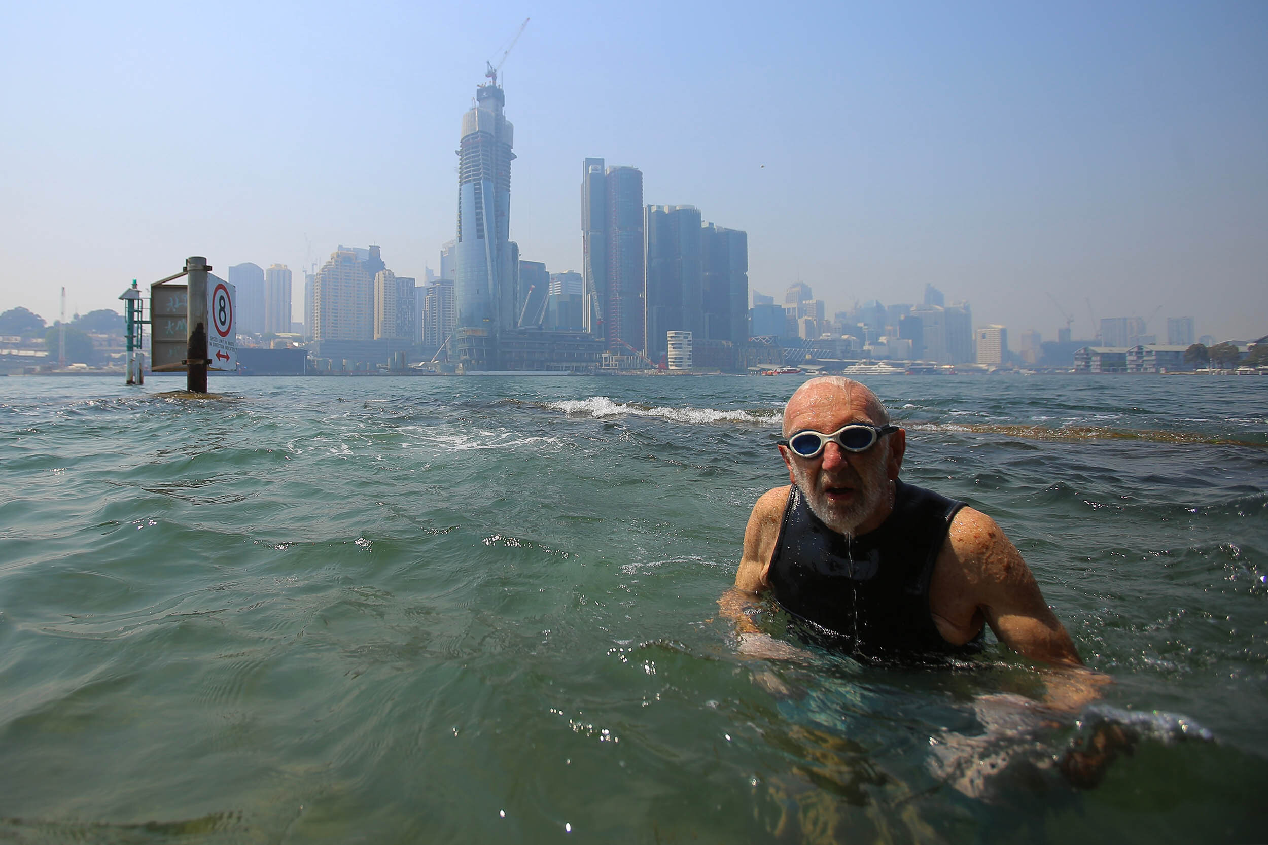  Frank Heatherton of Balmain swims in Sydney Harbour as smoke haze drifts over the CBD in Sydney, Thursday, October 31, 2019. Air quality readings in parts of NSW has reached hazardous levels as extensive smoke haze from fires in the state's north is