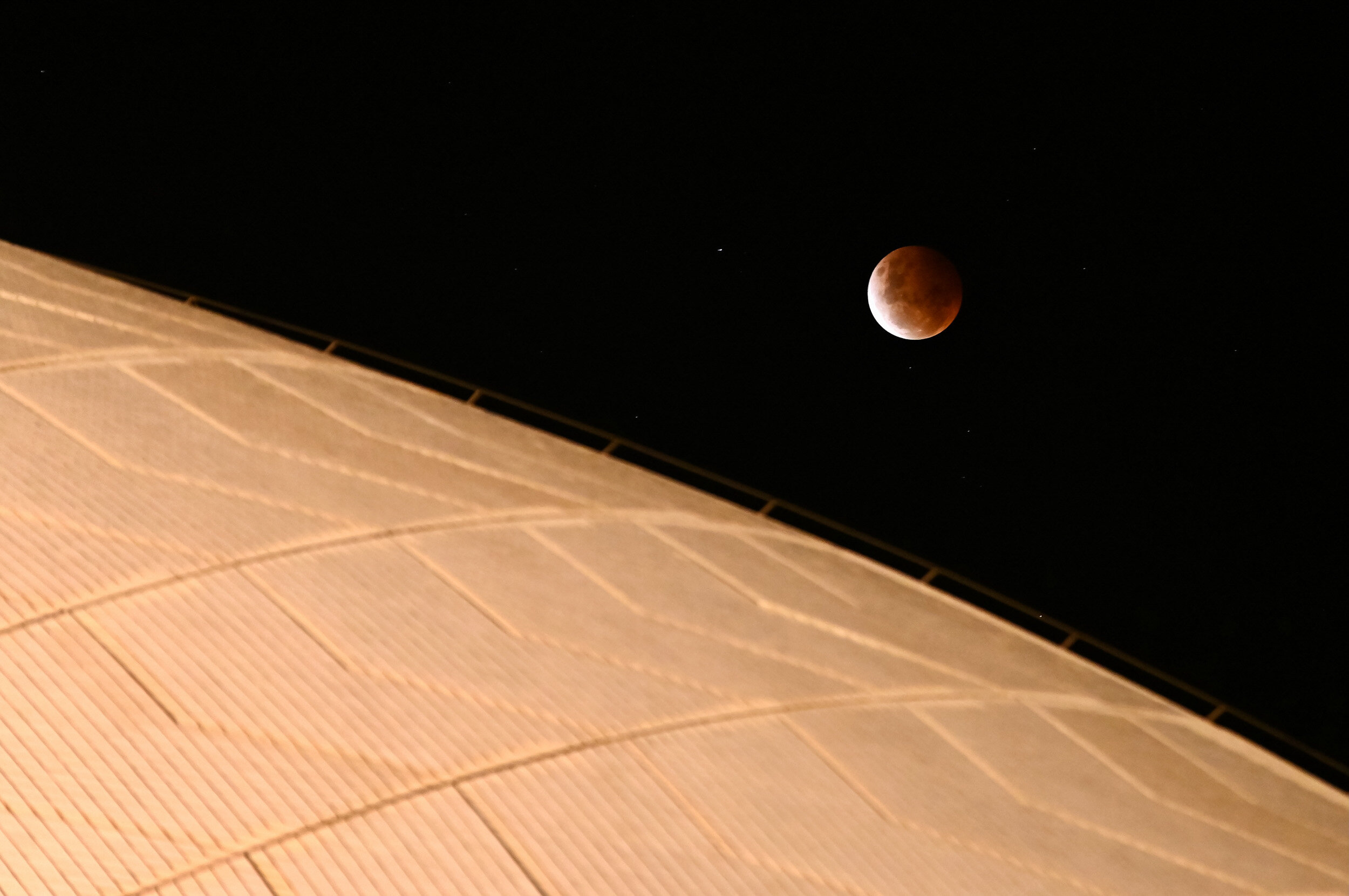  SYDNEY, AUSTRALIA - May 26: The full moon, known as a ‘super blood moon’, rises above the sails of the Sydney Opera House during its total lunar eclipse phase, in Sydney, Australia, on May 26, 2021.The full moon on Wednesday will be the year's bigge