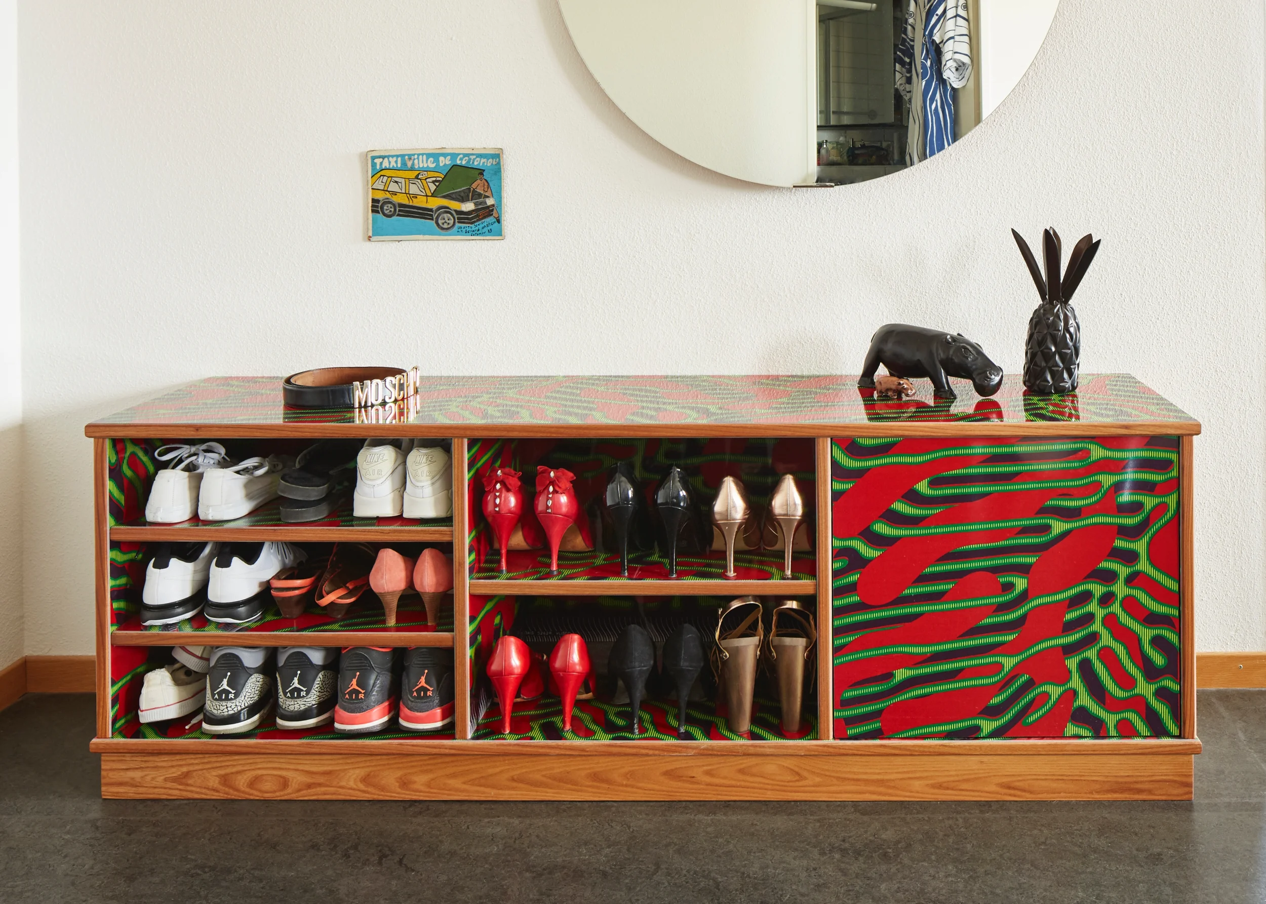 Ein edles Schuhregal für coole Schuhe. Die Oberflächen des Sideboards sind beschichtet mit afrikanischem Super-Wax Pagne. Der Stoff wurde in eine Kunstharzplatte eingepresst und hochglanz-beschichtet. Die Kanten sind aus geölter, einheimischer Ulme. Die stark gefasten Ecken geben dem Möbel seinen Charakter. Die Auswahl an Vlisco Super-Wax ist übrigens beinahe unerschöpflich: https://shop.vlisco.com