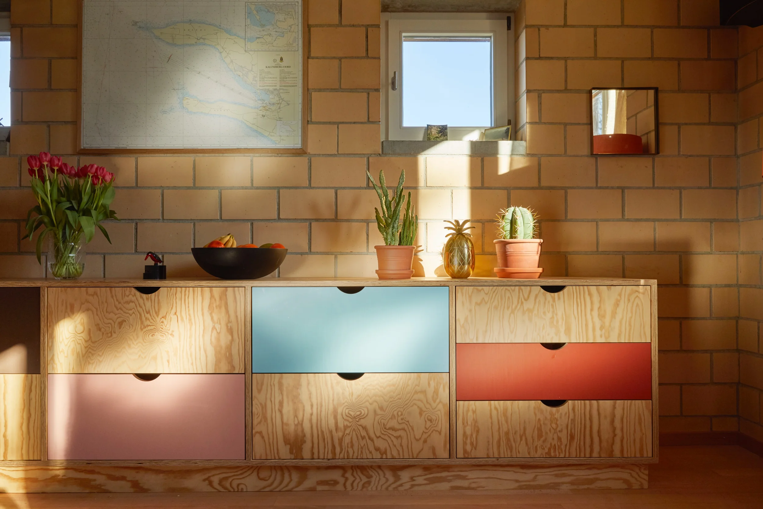 Die schlichte Küche ist mit modernster Küchentechnik ausgestattet. Neben einem Induktionskochfeld mit integriertem Dunstabzug, Backofen und Geschirrspüler, ist viel Platz für Vorräte und Küchengeräte in den grauen Auszügen im Unterbau vorhanden. In der Erweiterung ins Esszimmer kann neben dem grosszügigen Kühlschrank viel Geschirr, Besteck und Küchenwäsche in den Holzschubladen untergebracht werden.