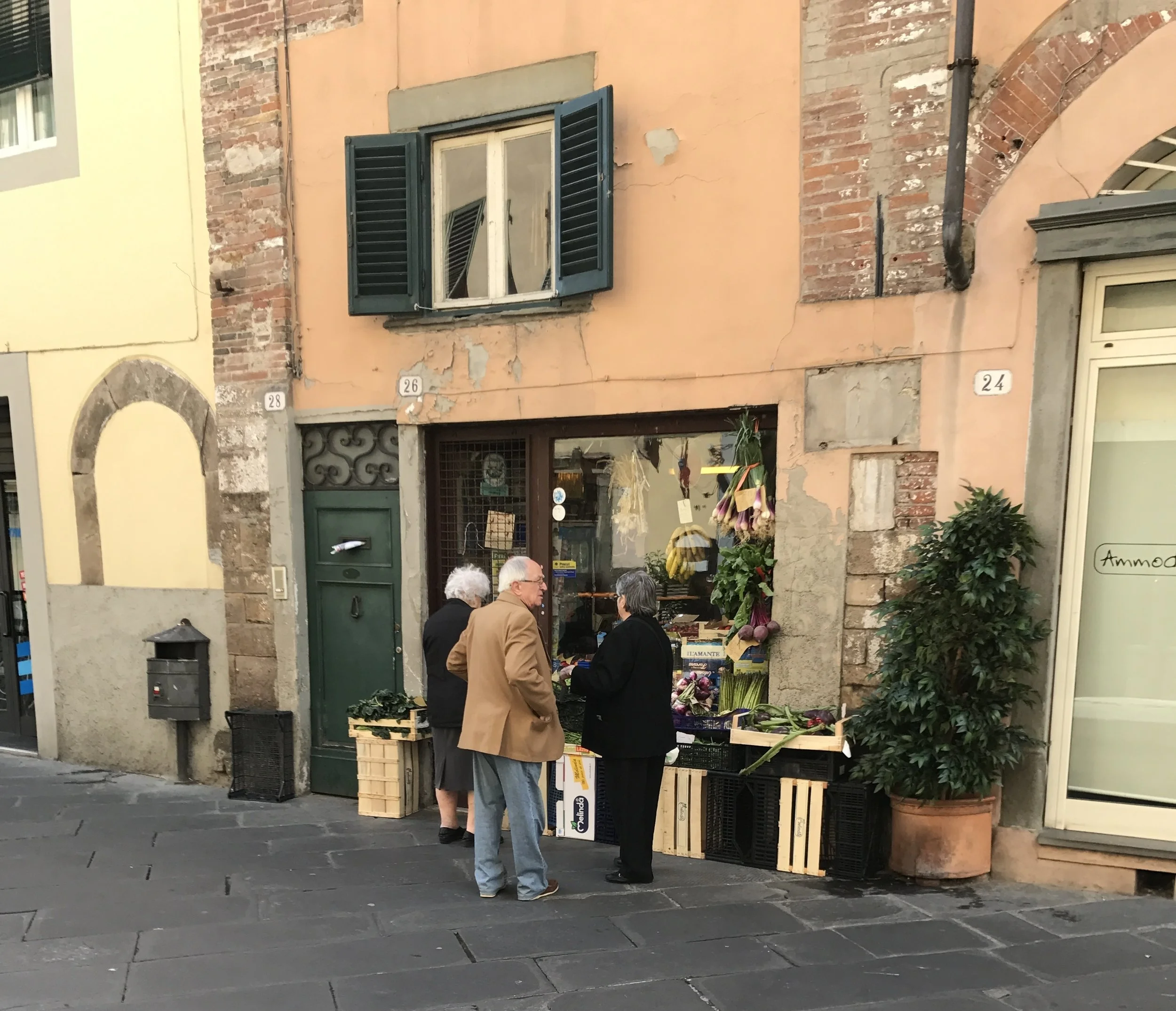 Neighbors chat outside a produce store.