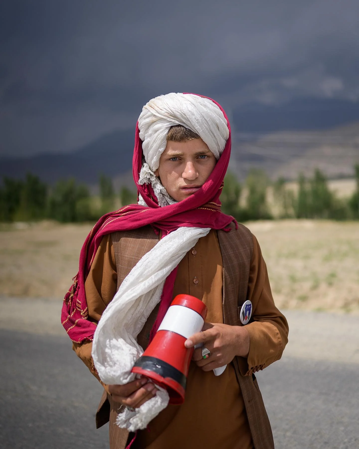 Abibullah, 15, stand next to a segment of the main road in Saydabad was damaged by an IED blast. He chose this spot because drivers have to slow down and he can, armed with his megaphone, ask them to donate to his madrassa. 

Saydabad district, in Ma