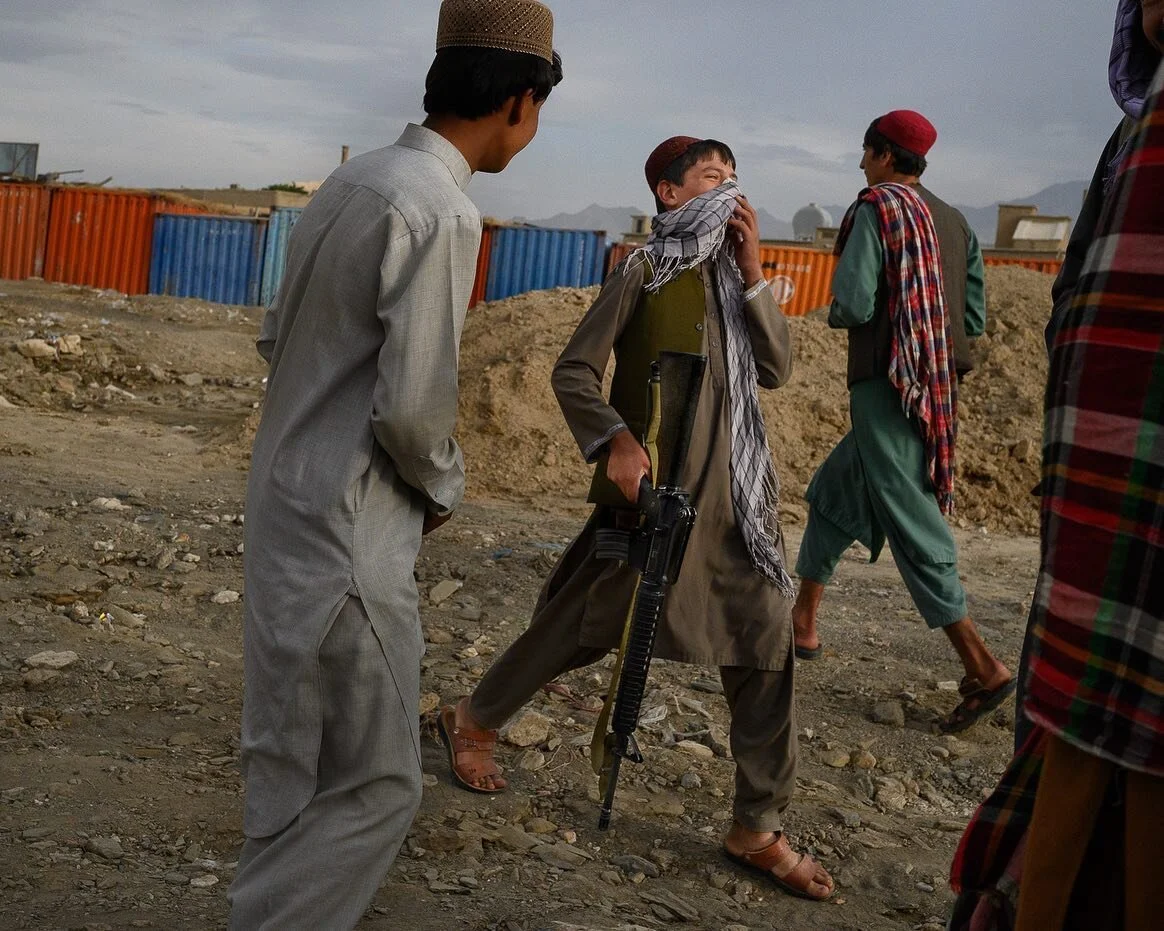 Guns and graves. Two images taken at different times but standing in the same spot in Saidabad. 
A boy laughs as he runs toward the cemetery to bring his M16&ndash;taken from the US army&mdash;to &lsquo;Talib jan&rsquo;, a local commander.
Further on