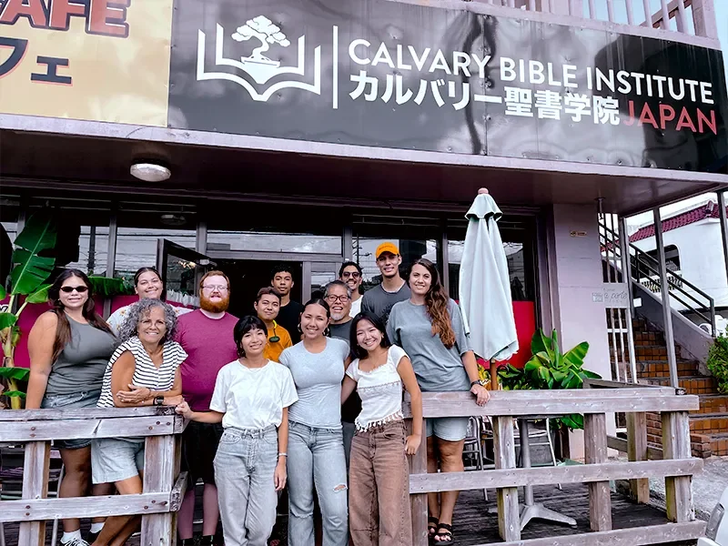 Group of people standing outside Calvary Bible Institute in Japan, posing for a photo.