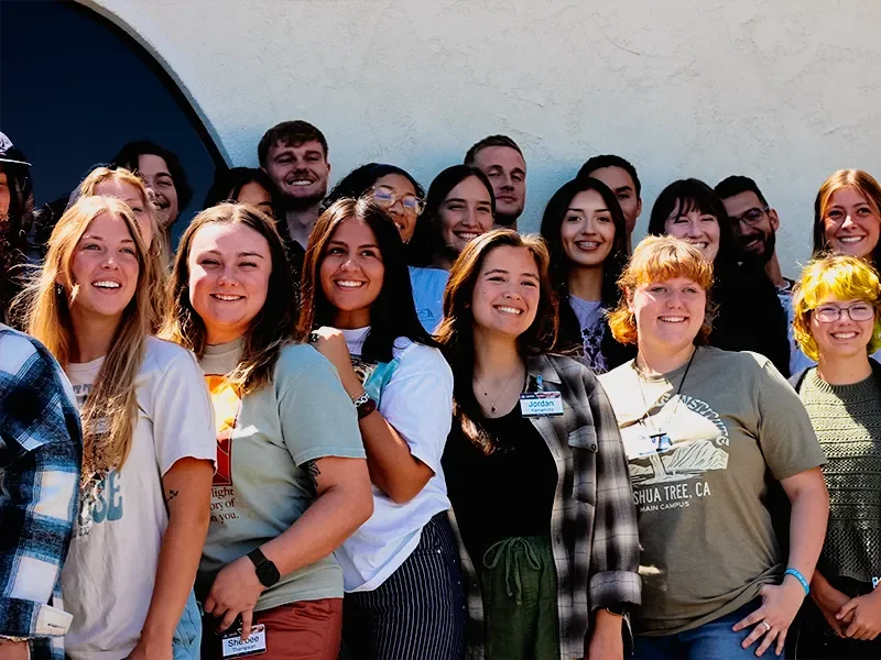 Group of young adults smiling outdoors in front of a building.